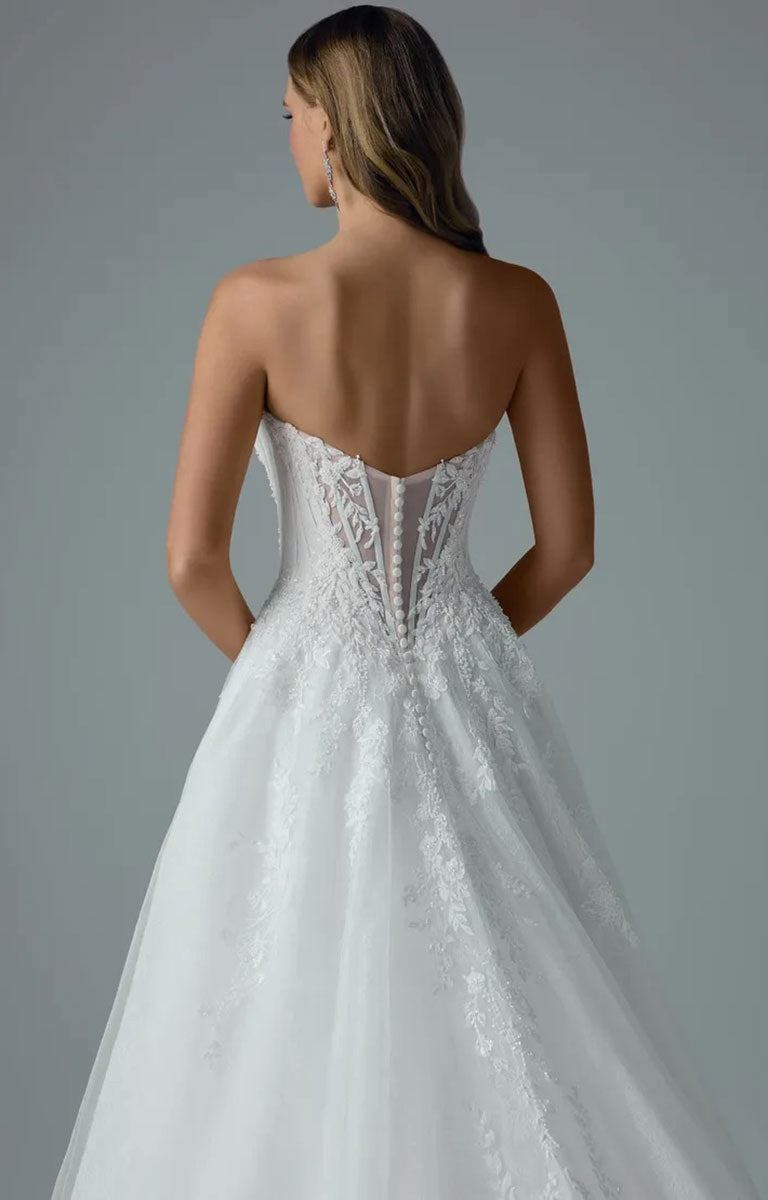 A woman shown from the back wearing Neeve Y3237 by Sophia Tolli - Strapless Lace Ball Gown Wedding Dress with Glitter Tulle with a lace-embellished corset-style bodice and a full tulle skirt, photographed against a plain gray studio background.