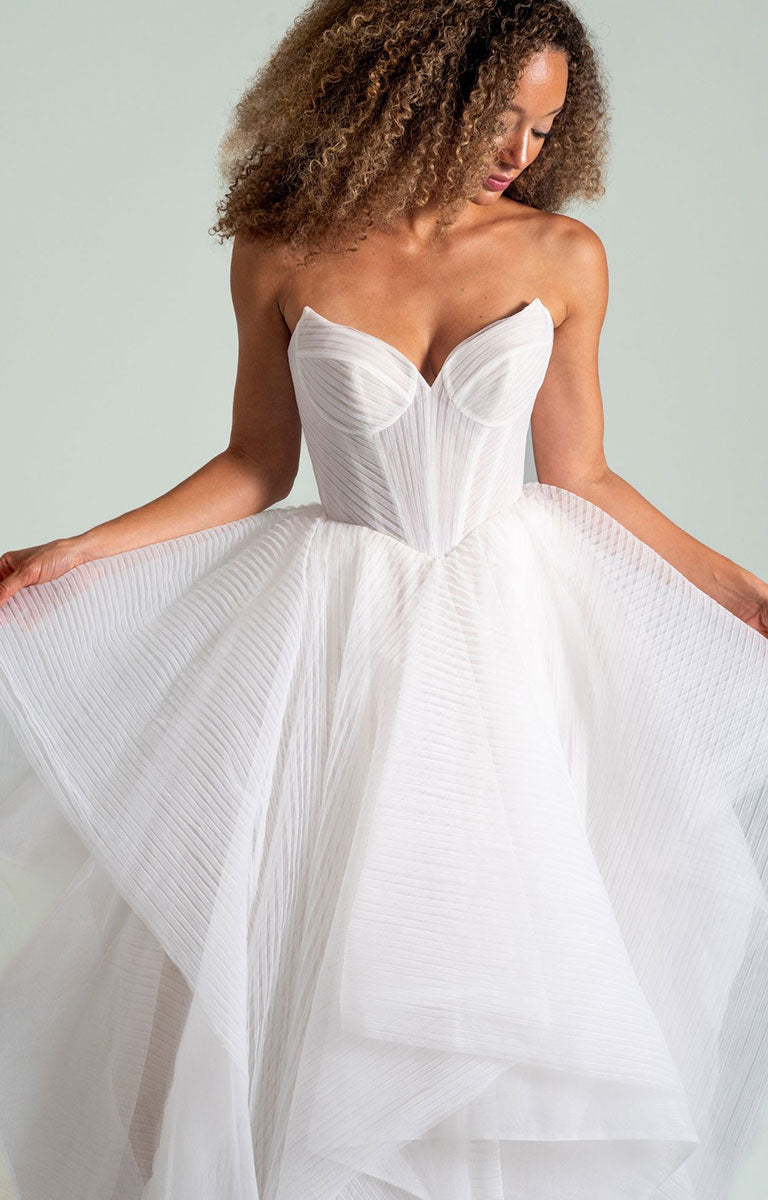 Woman wearing Once I Was a Swan by Hayley Paige - Layered Tulle Ballgown Wedding Dress with Corset Bodice with a flowing skirt against a light background