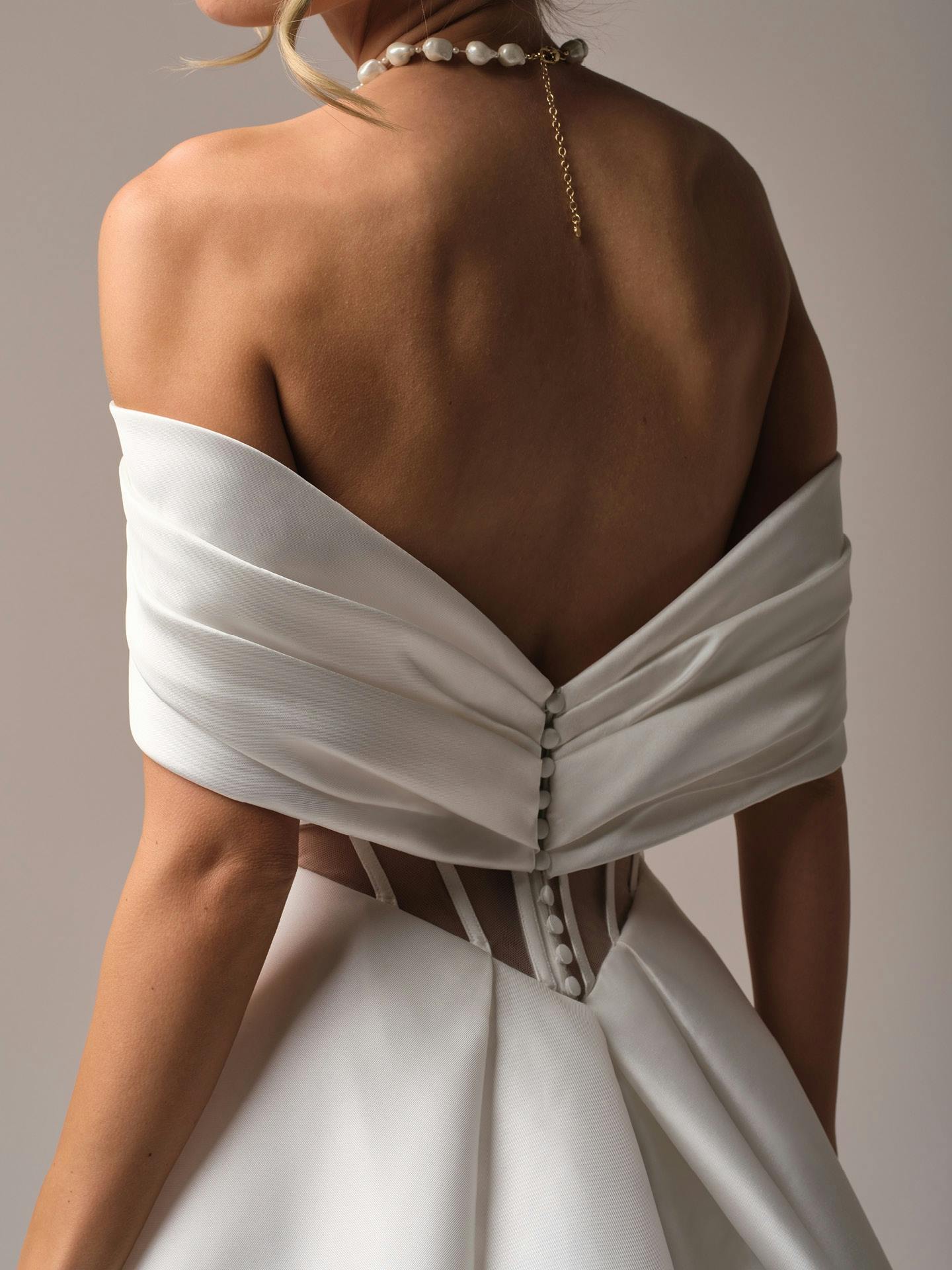 White off-shoulder dress with open back on a neutral background