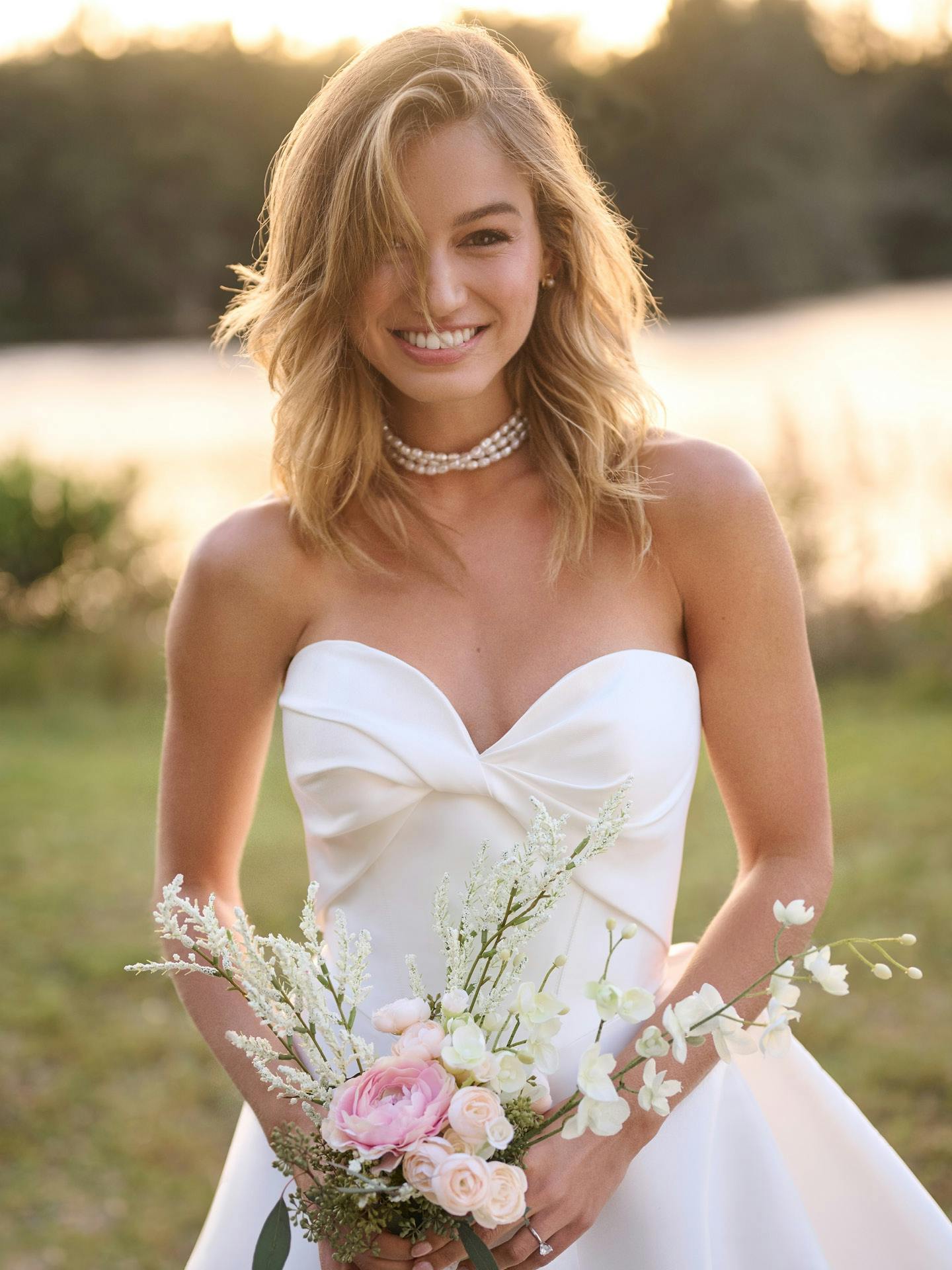 Woman in a white wedding dress holding flowers in a natural setting