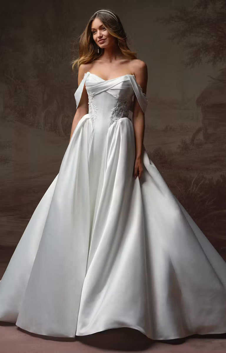 A woman modelling Gigi by Rebecca Ingram - 3D Floral Satin Ball Gown with Deep Basque Waist and Detachable Panniers made of white satin, featuring a sweetheart neckline, structured bodice, and full skirt, set against a dark, painterly background.