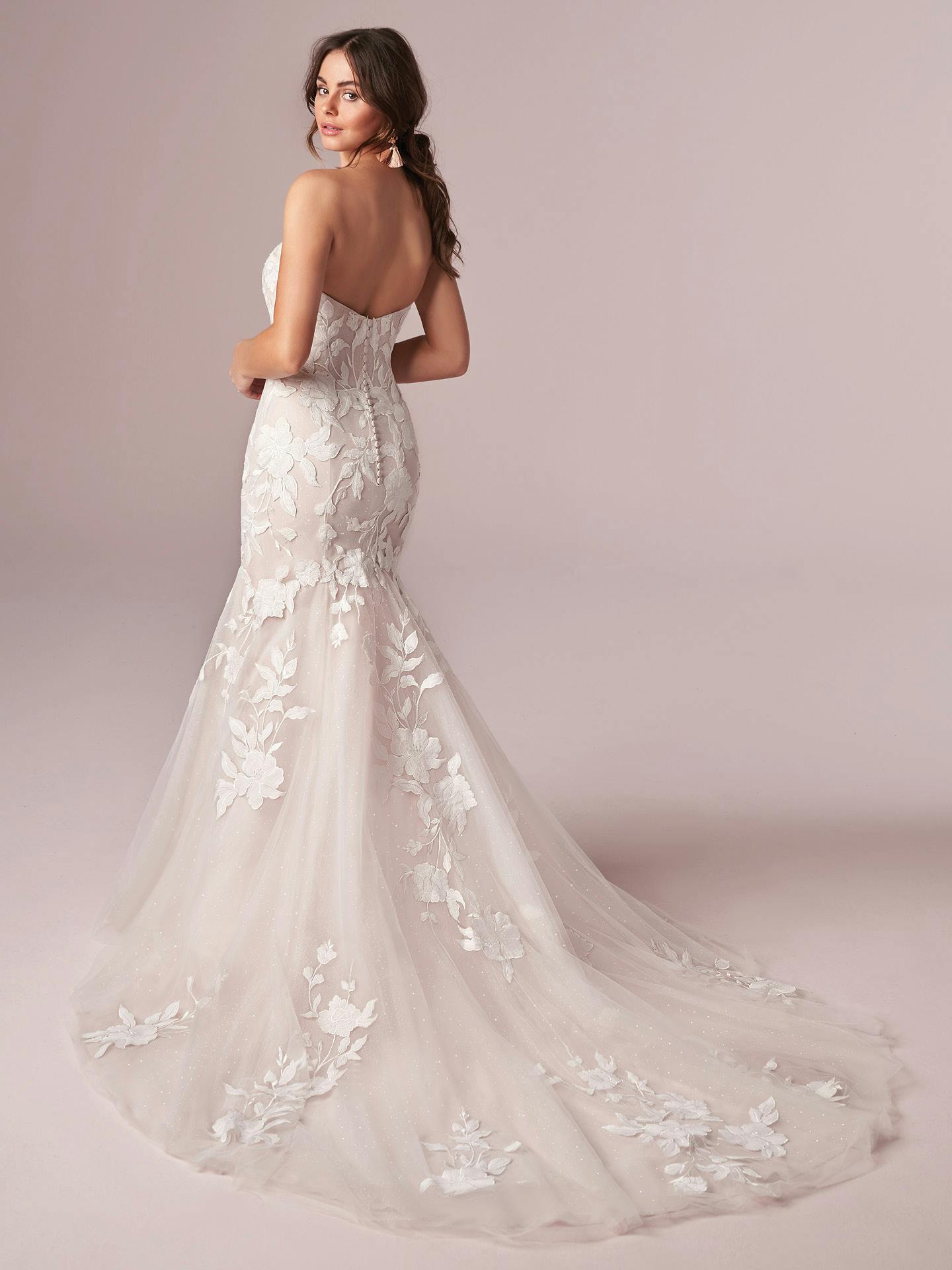 Woman wearing Hattie by Rebecca Ingram - a white floral wedding dress against a light pink background