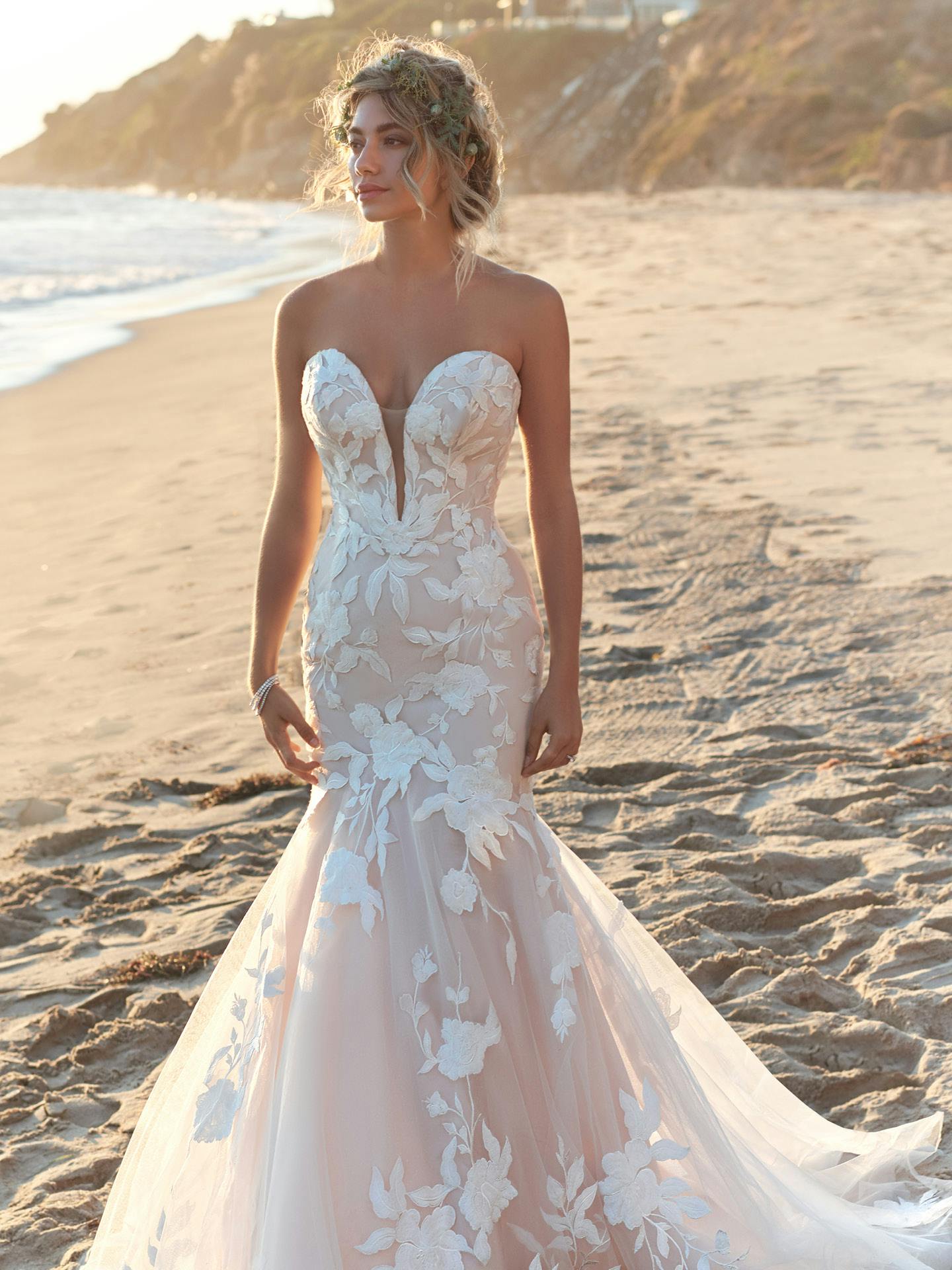 Woman in Hattie by Rebecca Ingram - a white lace wedding dress on a beach