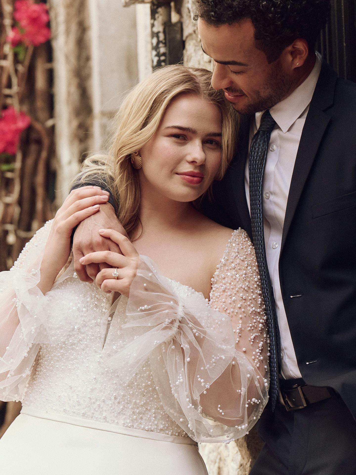 Man and woman embracing in a romantic setting with flowers in the background