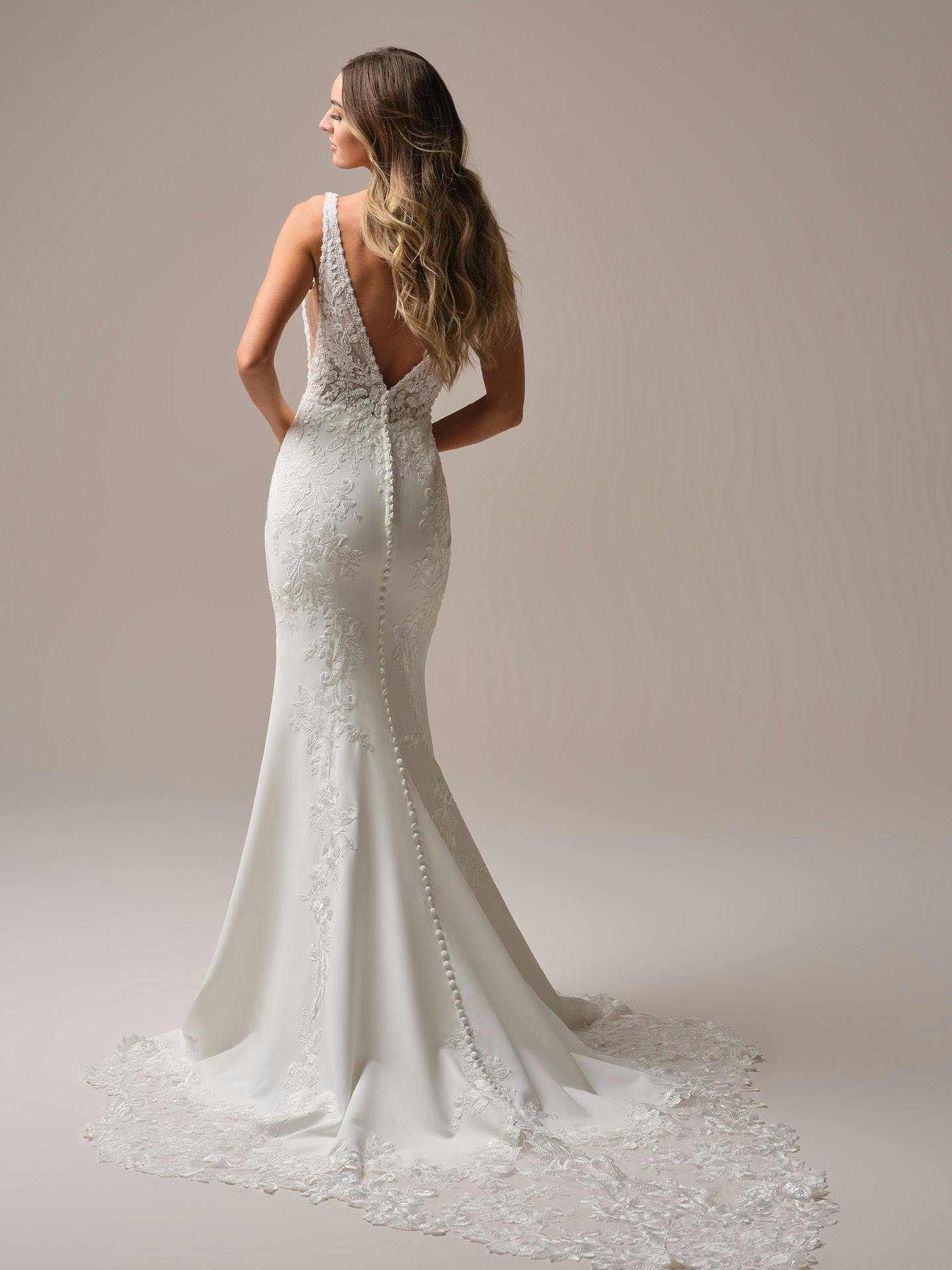 Woman wearing a white lace wedding dress with a plain background