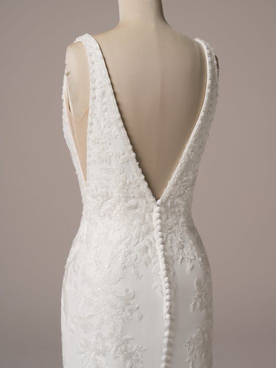 White lace wedding dress on a mannequin with a plain background
