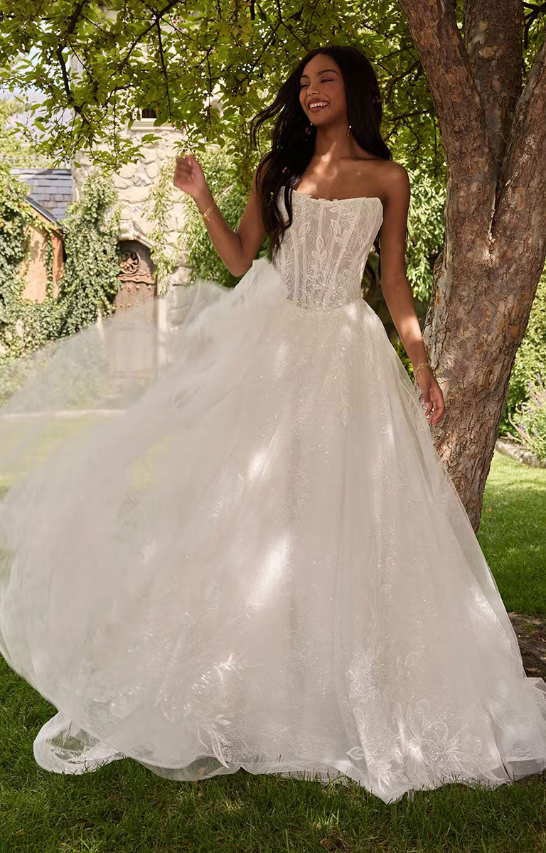 Woman in Lisa by Rebecca Ingram - Cat Eye Neckline Illusion Lace Ballgown Wedding Dress standing outdoors near a tree