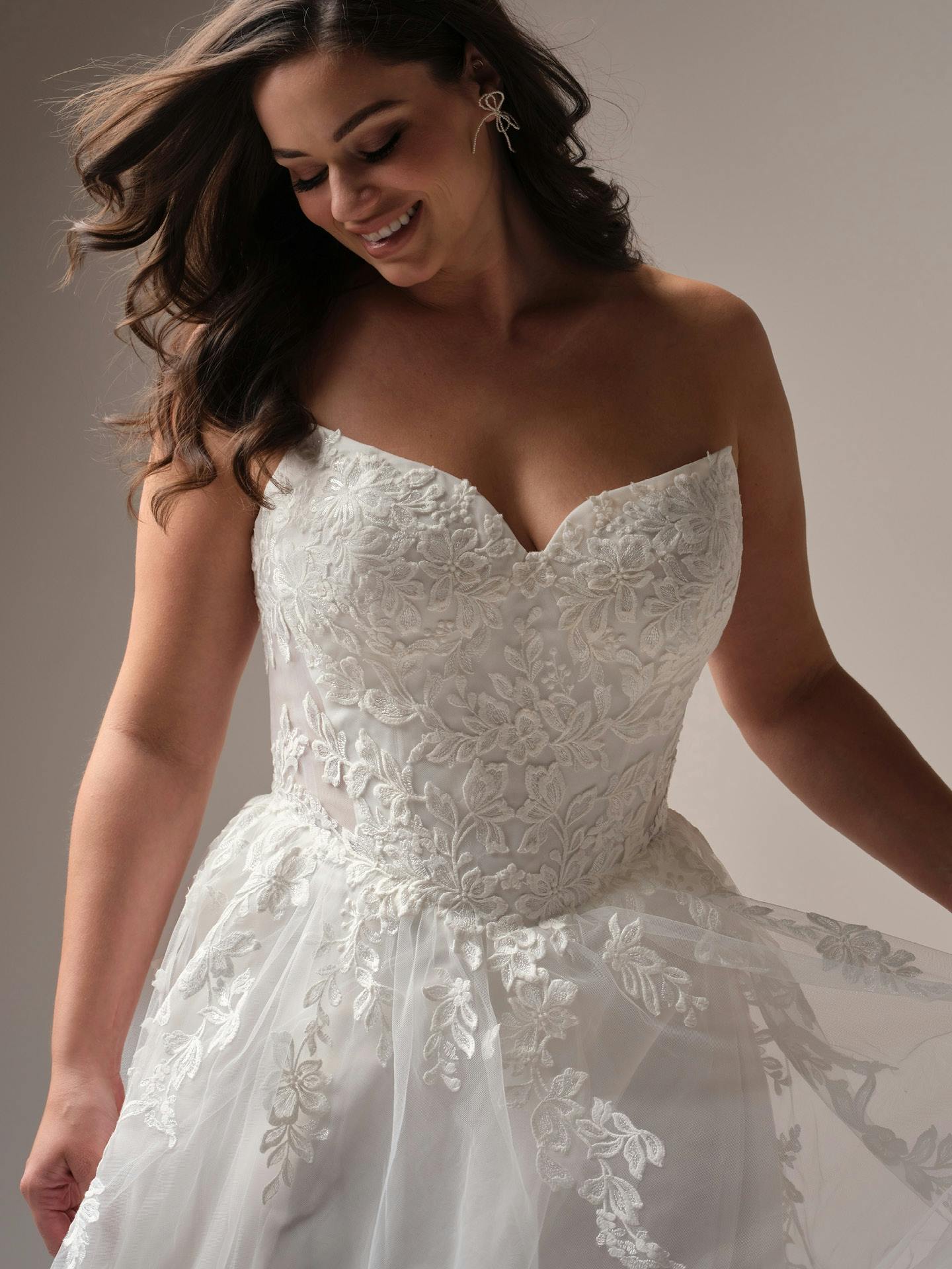 Woman wearing a white lace wedding dress against a neutral background