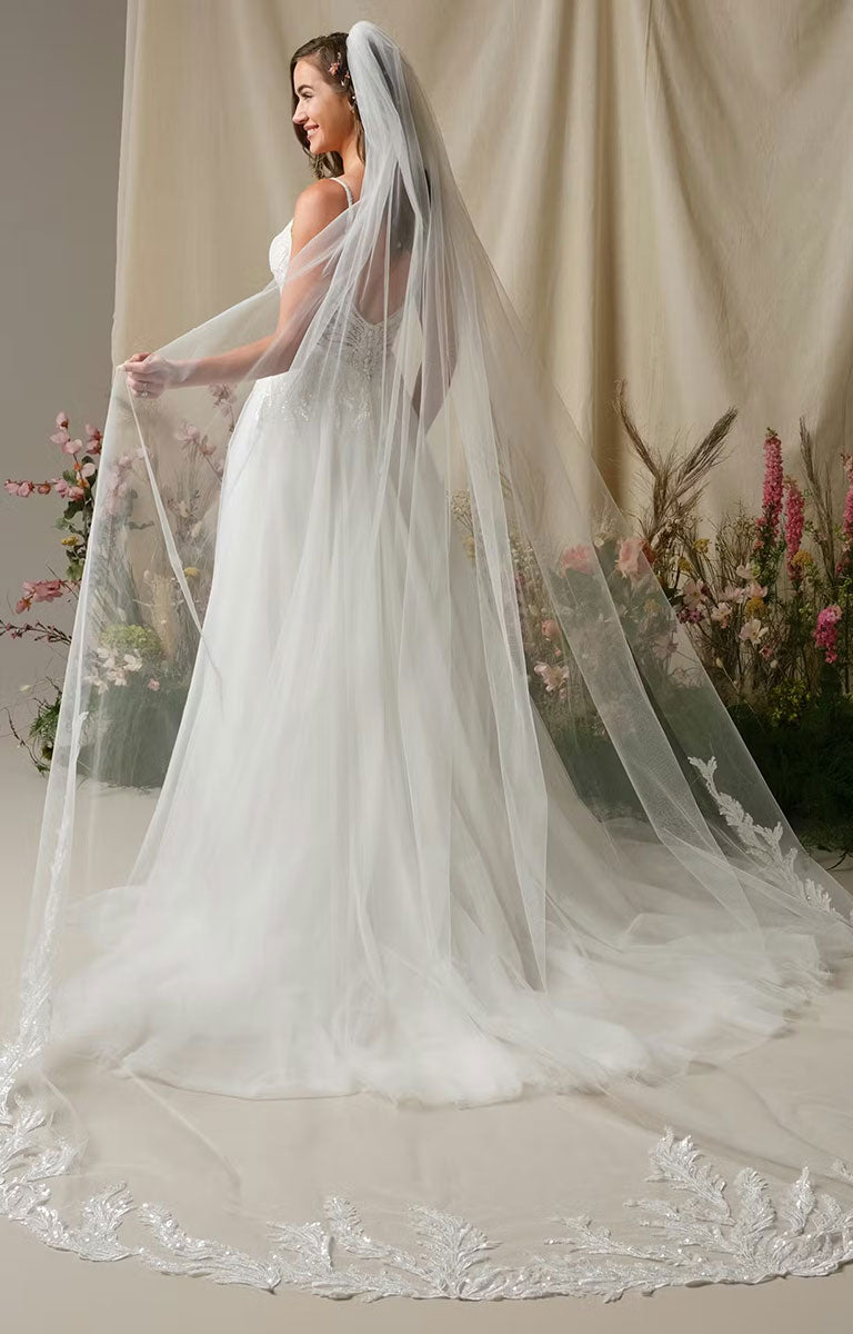 Woman wearing Valarie by Rebecca Ingram - Sparkle Lace A-Line Wedding Dress with Plunging V-Neck and Side Slit with floral details against a neutral background.