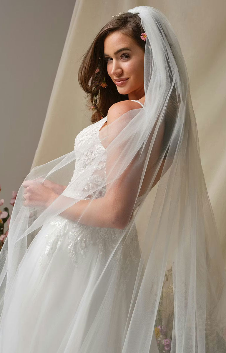 Woman wearing Valarie by Rebecca Ingram - Sparkle Lace A-Line Wedding Dress with Plunging V-Neck and Side Slit against a neutral background