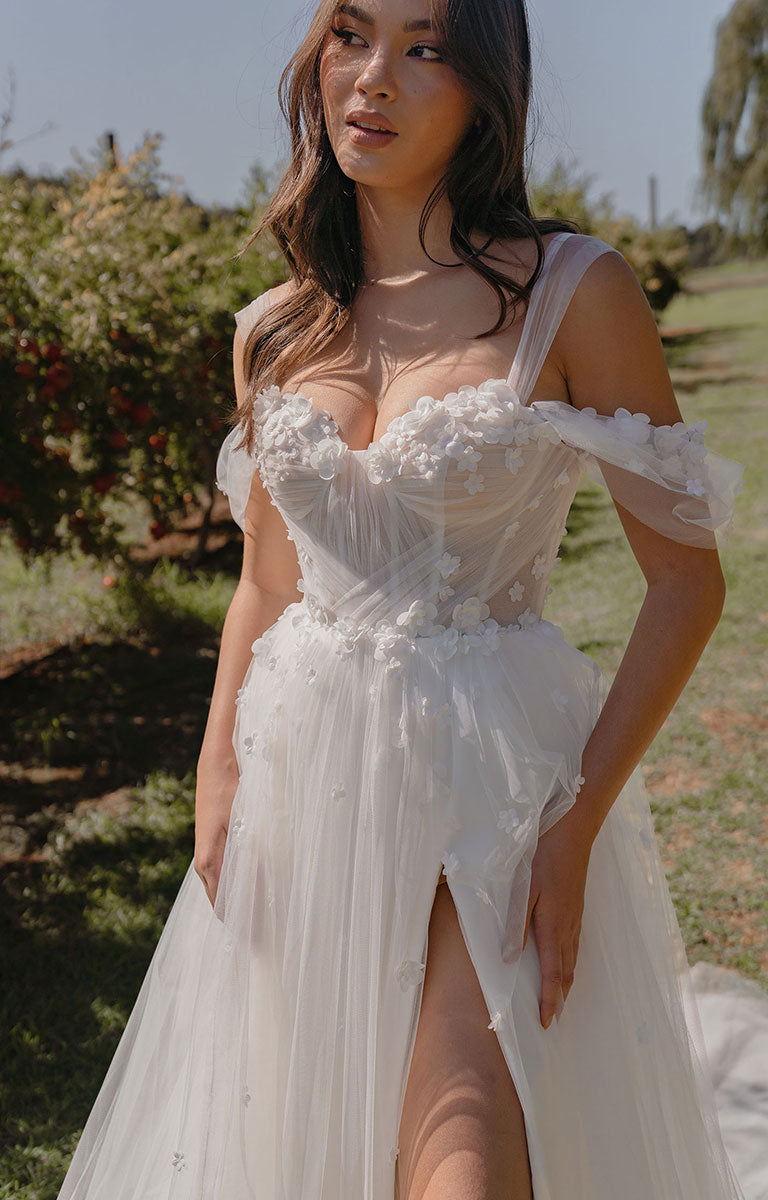 Woman wearing a white floral dress with a slit in a garden setting