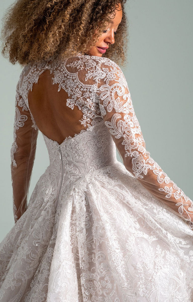 Woman wearing She Who Hung the Moon by Hayley Paige - Lace Ballgown Wedding Dress with Detachable Bolero with long sleeves against a plain background