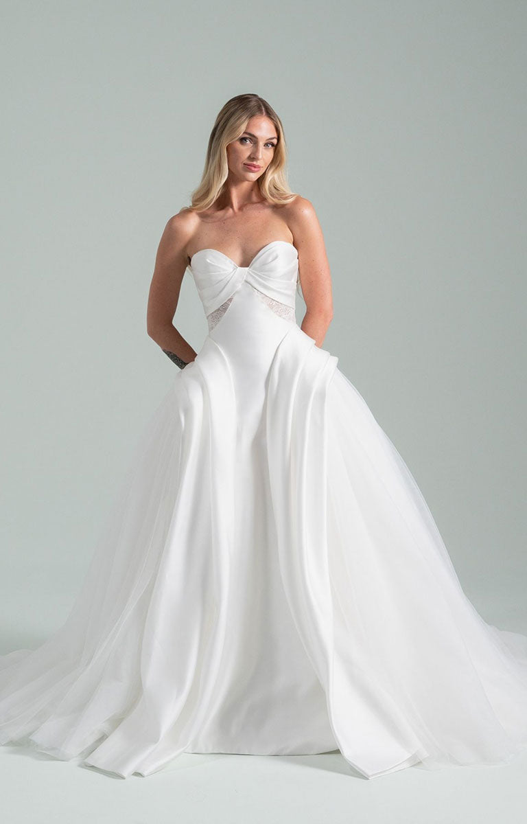 Woman wearing Sonnet 104 by Hayley Paige - Satin and Tulle Ballgown Wedding Dress with Draped Corset Bodice on a gray background
