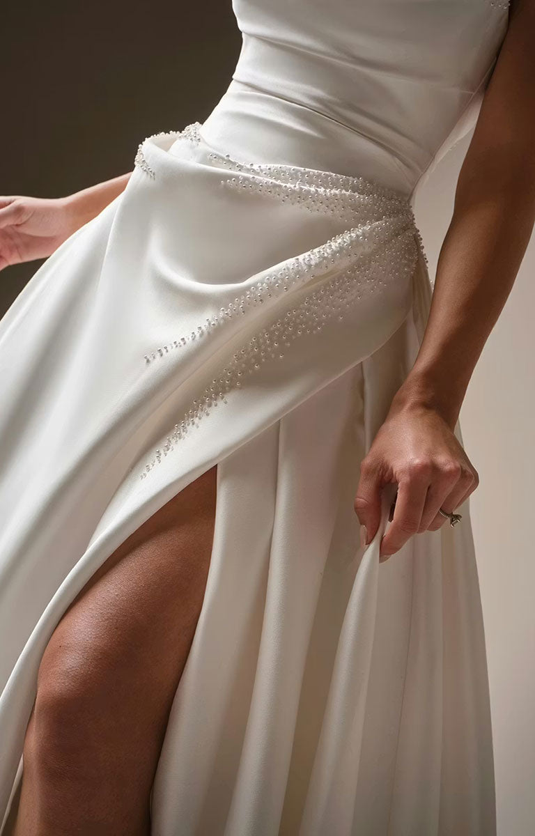 Kincaid by Sottero and Midgley - Ruched Satin Ballgown Wedding Dress with Pearl Details and Cat-Eye Neckline with a high slit and beaded details on a neutral background