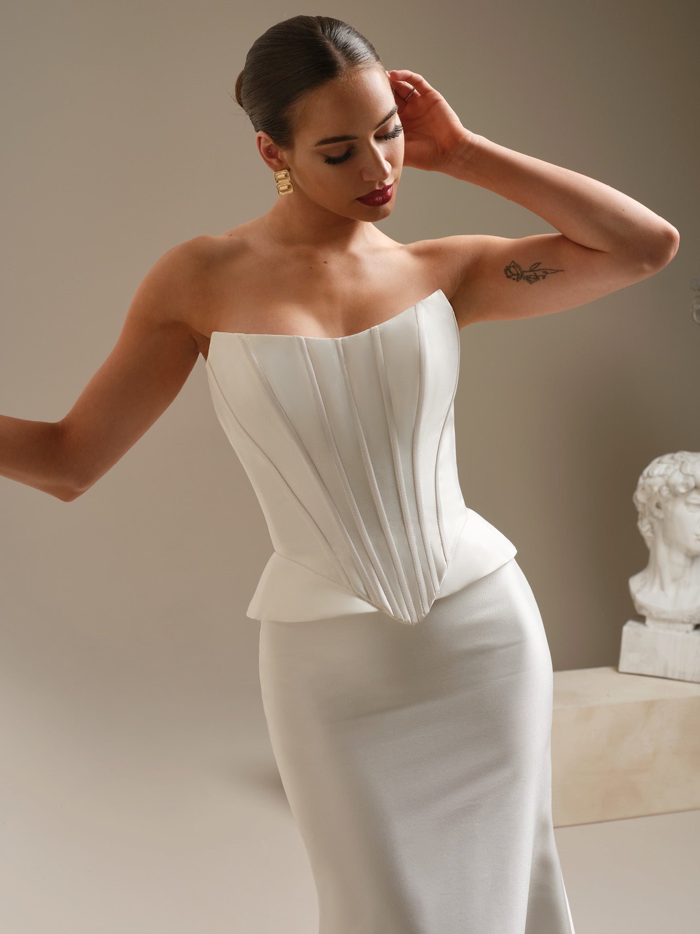 Woman wearing Sottero and Midgley - Strapless Chantilly Lace Sheath Wedding Dress with Cat-Eye Neckline and Corset Bodice against a neutral background