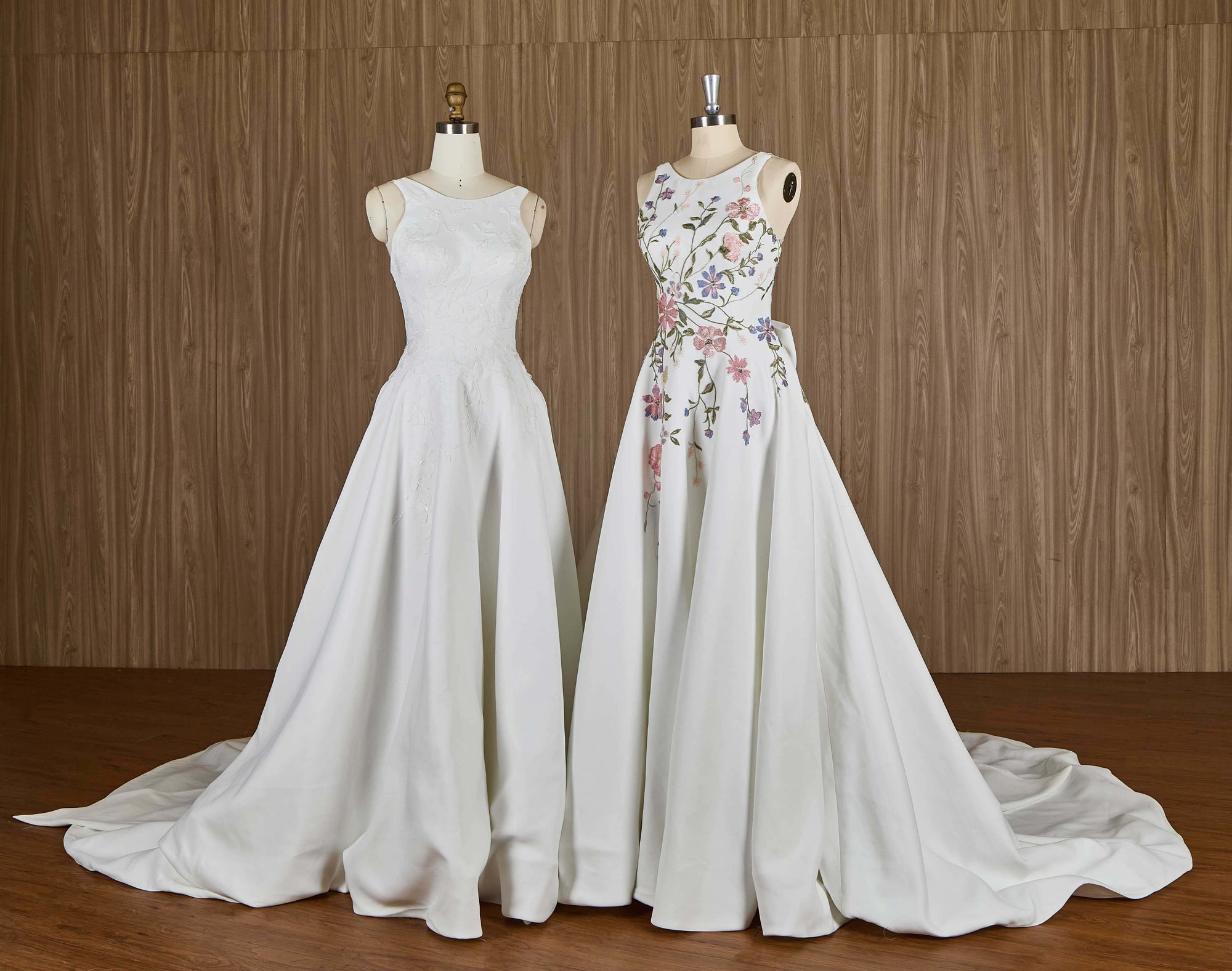 Two wedding dresses on mannequins against a wooden background