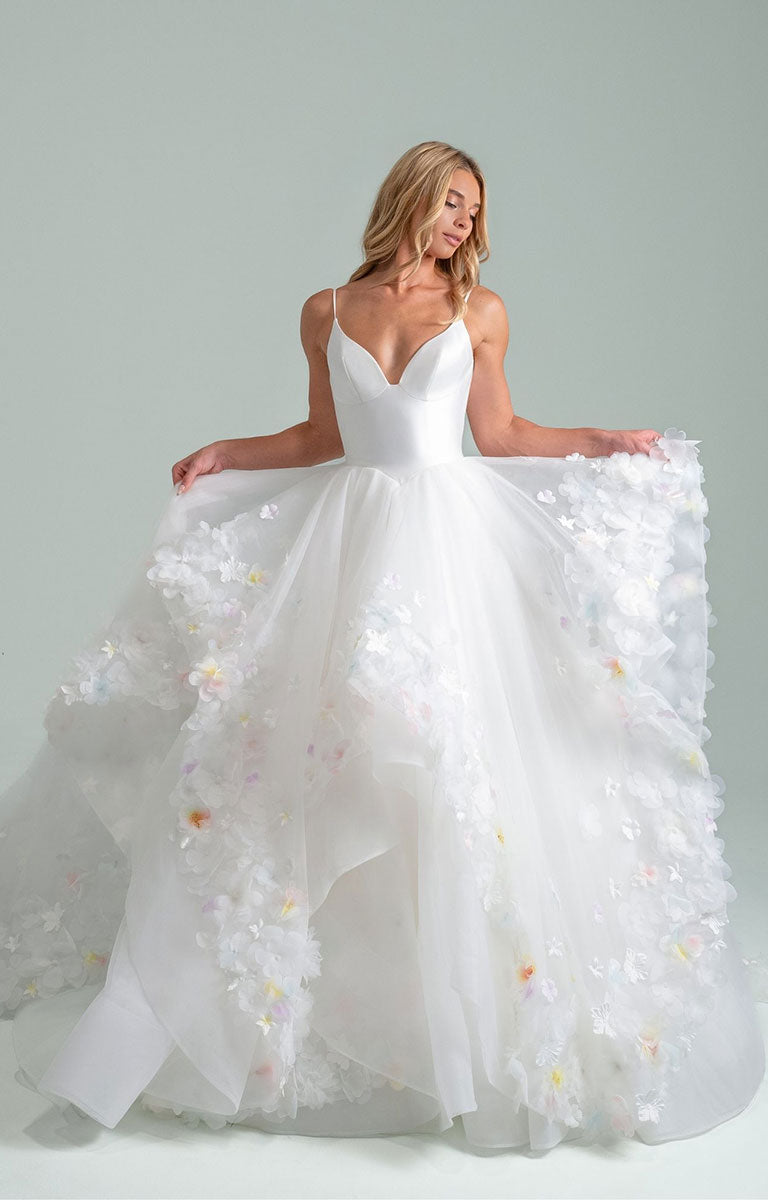 Woman wearing Turning Paiges by Hayley Paige - Layered Organza Ballgown Wedding Dress with Floral Petal Detail against a plain background