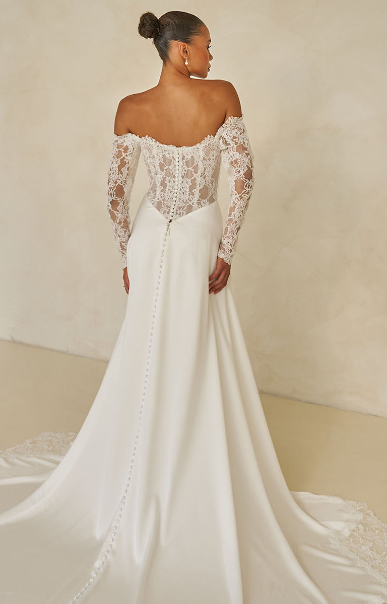 Ward by Madi Lane Bridal - White wedding dress with lace detailing on a plain background