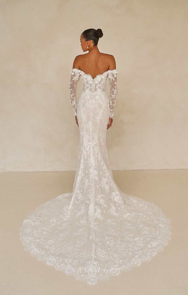 White lace wedding dress with long sleeves on a plain background