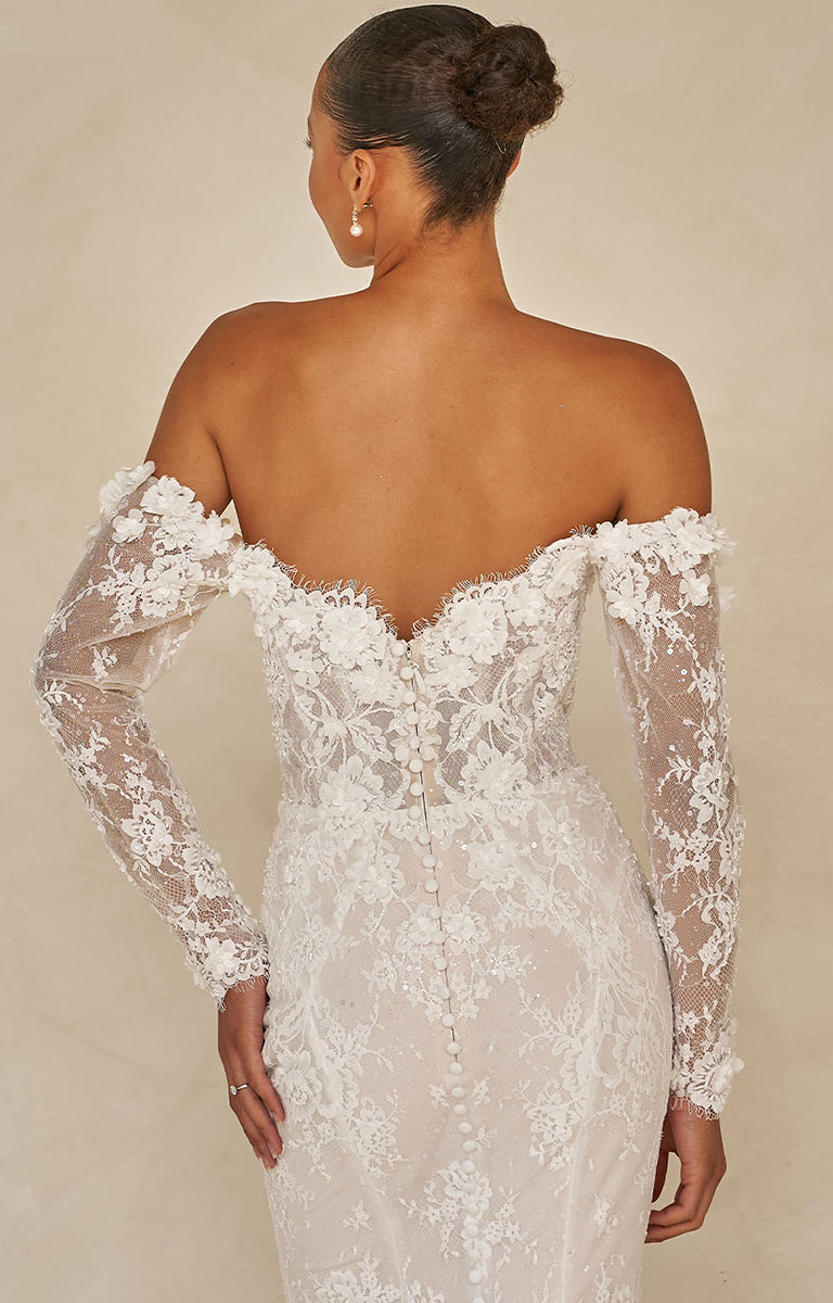 White lace wedding dress with long sleeves on a neutral background