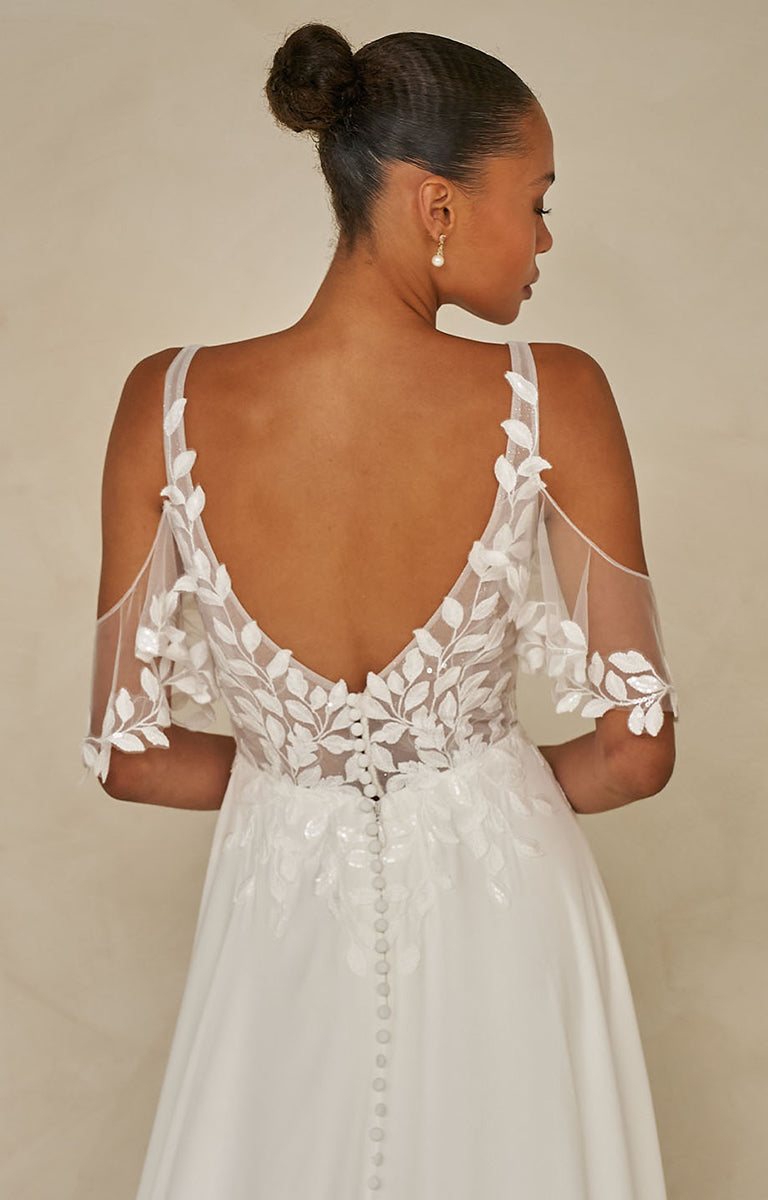 Wilmott by Madi Lane - White wedding dress with floral lace details on a plain background