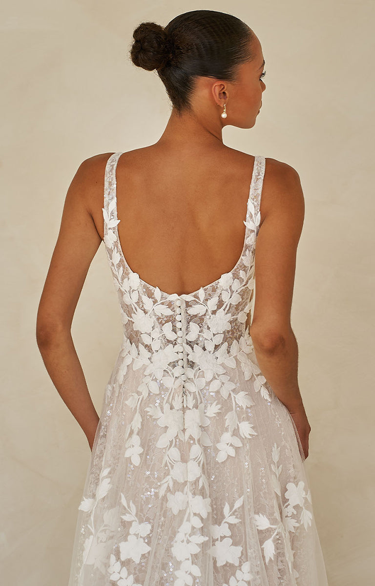 Woman wearing Wimmer by Madi Lane, a floral lace dress with an open back against a beige background