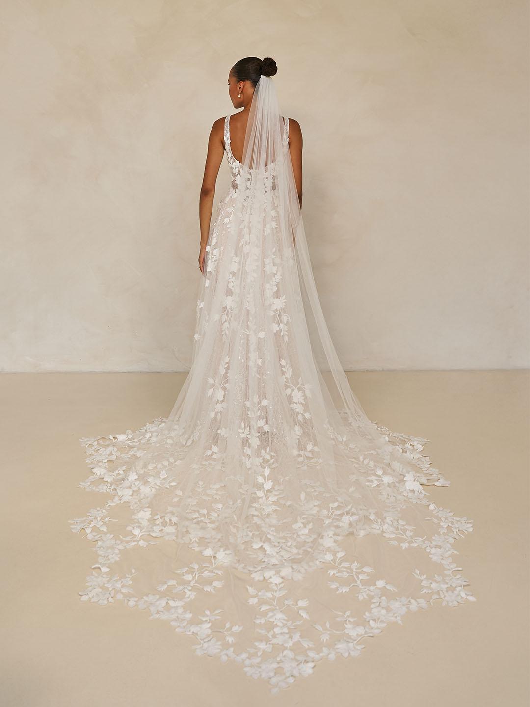 Bride wearing Wimmer by Madi Lane, a long, elegant wedding dress with a matching veil against a neutral background