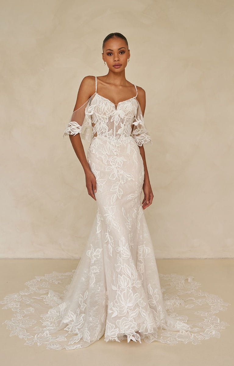 Model wearing Winona by Madi Lane, a white lace wedding dress against a beige background