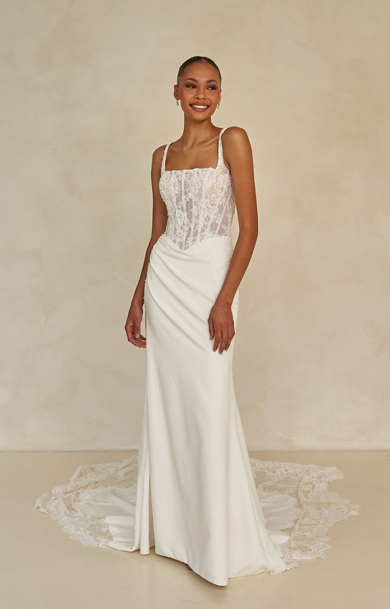 Woman wearing Wright by Madi Lane, a white wedding dress with lace detailing on a neutral background