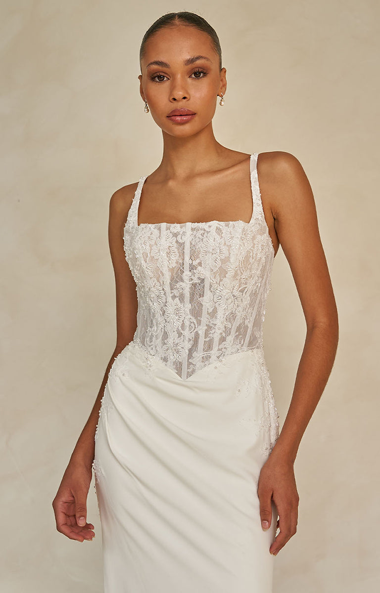 Woman wearing Wright by Madi Lane, a white lace dress against a beige background