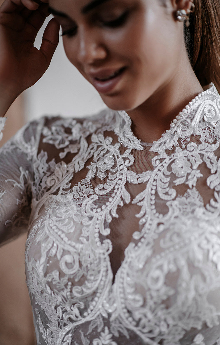 Close-up of a person wearing a lace dress with intricate detailing.