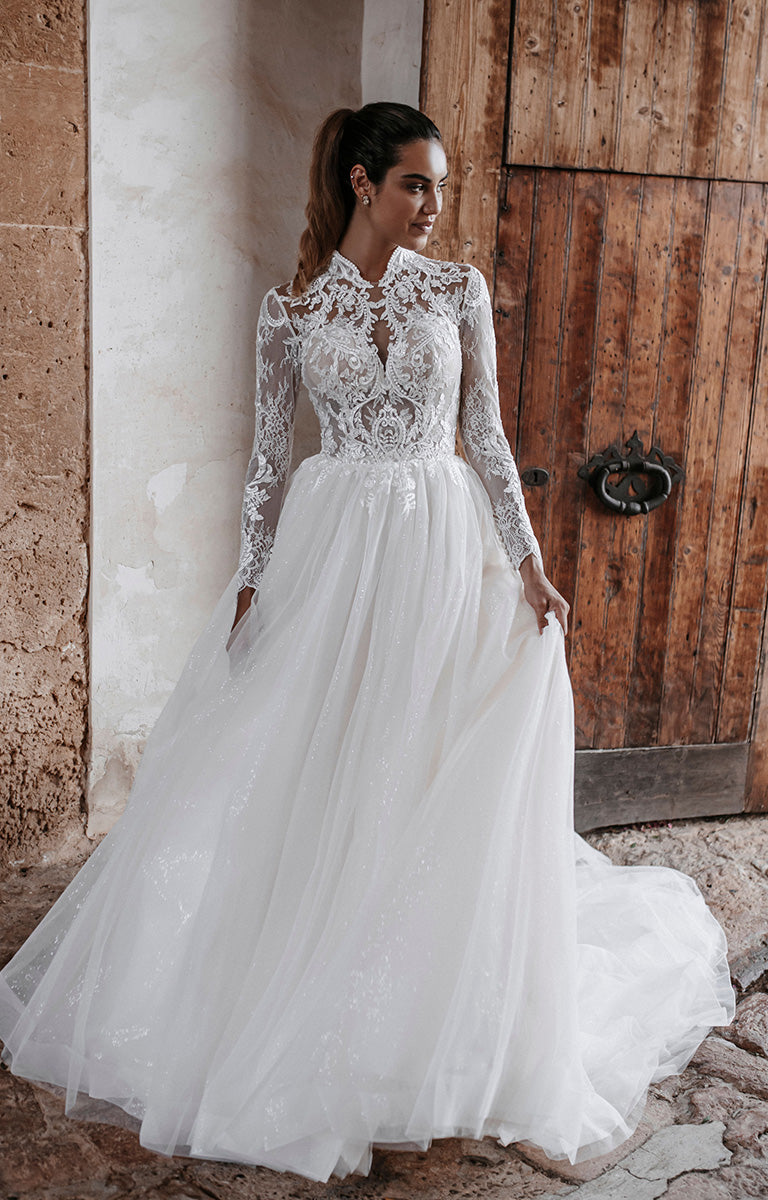 Woman in a white lace wedding dress standing against a rustic wooden door.