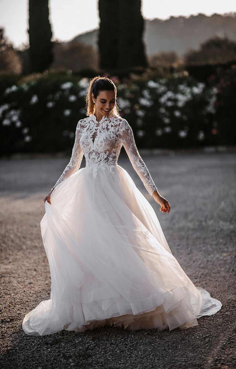 Woman in a white wedding dress standing outdoors with trees in the background