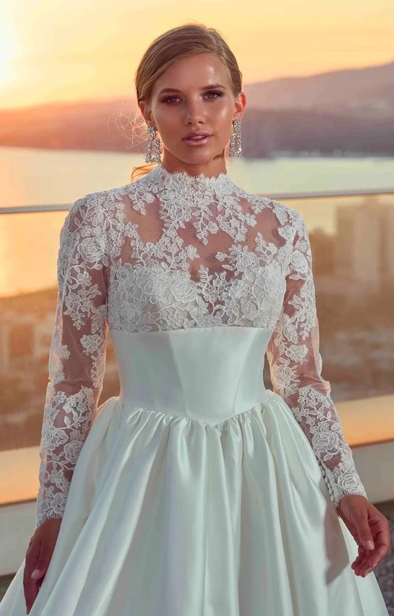 Woman wearing Legacy by Eddy K - Mikado Ballgown Wedding Dress with Lace Sleeves and Structured Waistband with a scenic background