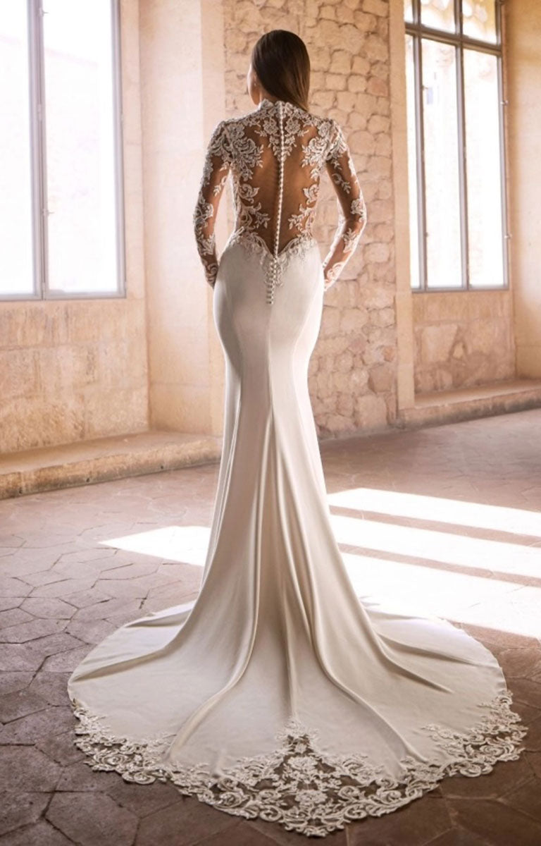 A woman wearing Glenda by Étoile Bridal - Lace Column Wedding Dress with Illusion Neckline and Long Sleeves