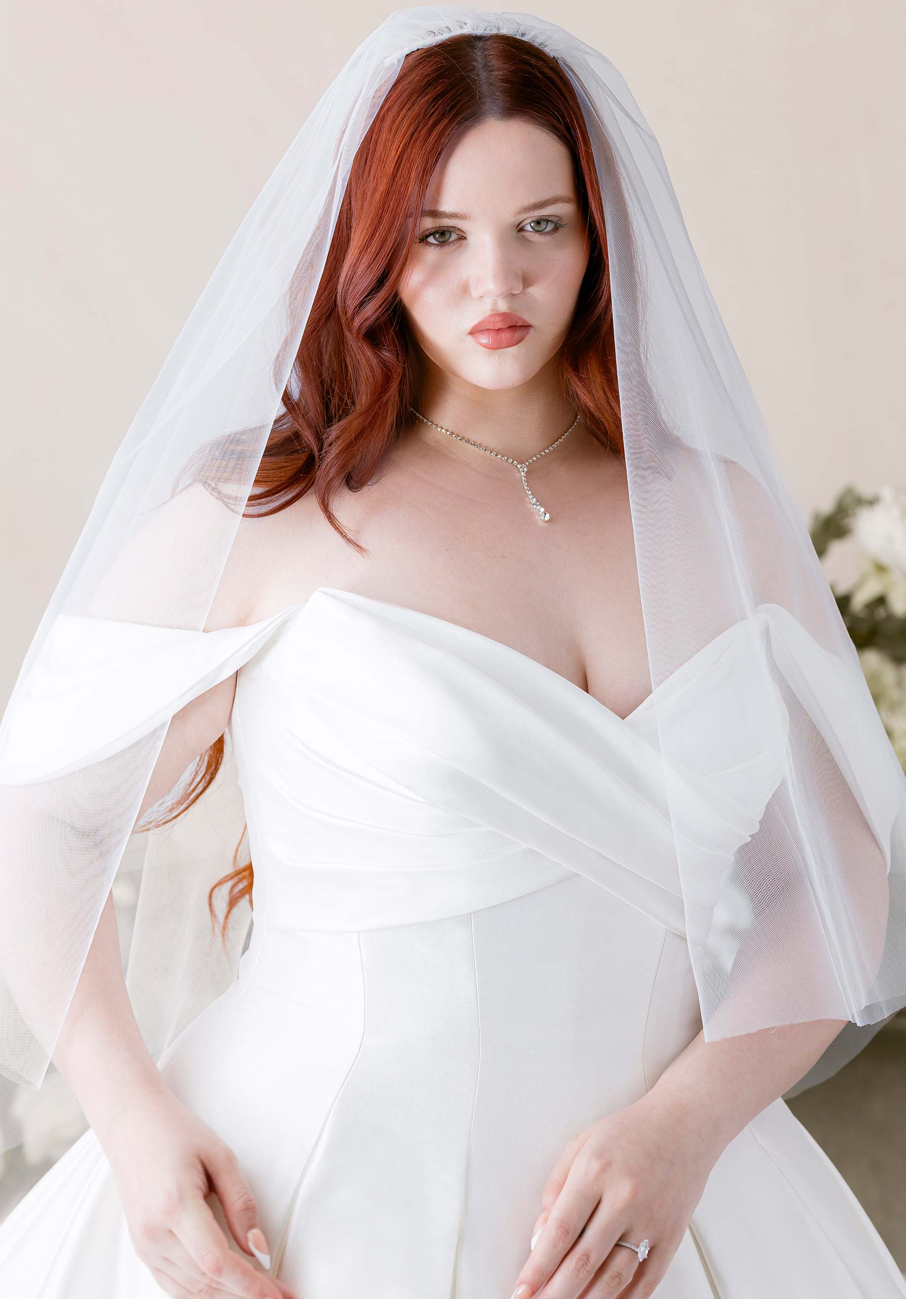 Woman wearing Kalina by Morilee - Ball Gown with Cat-Eye Neckline and Detachable Off-the-Shoulder Sleeves with a veil against a neutral background