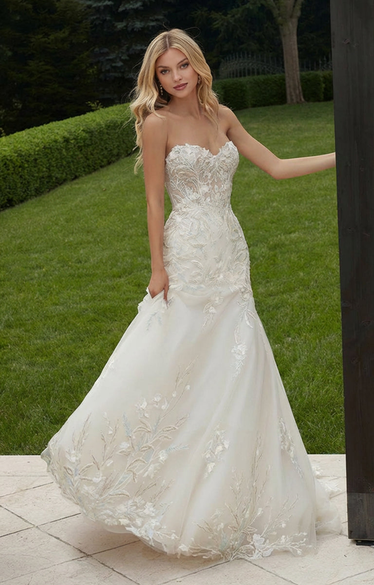 Woman in Persephone Wedding Dress by Morilee - Style 2608 - Floral Embroidered Mermaid Gown with Detachable Sleeves standing outdoors on a grassy area.