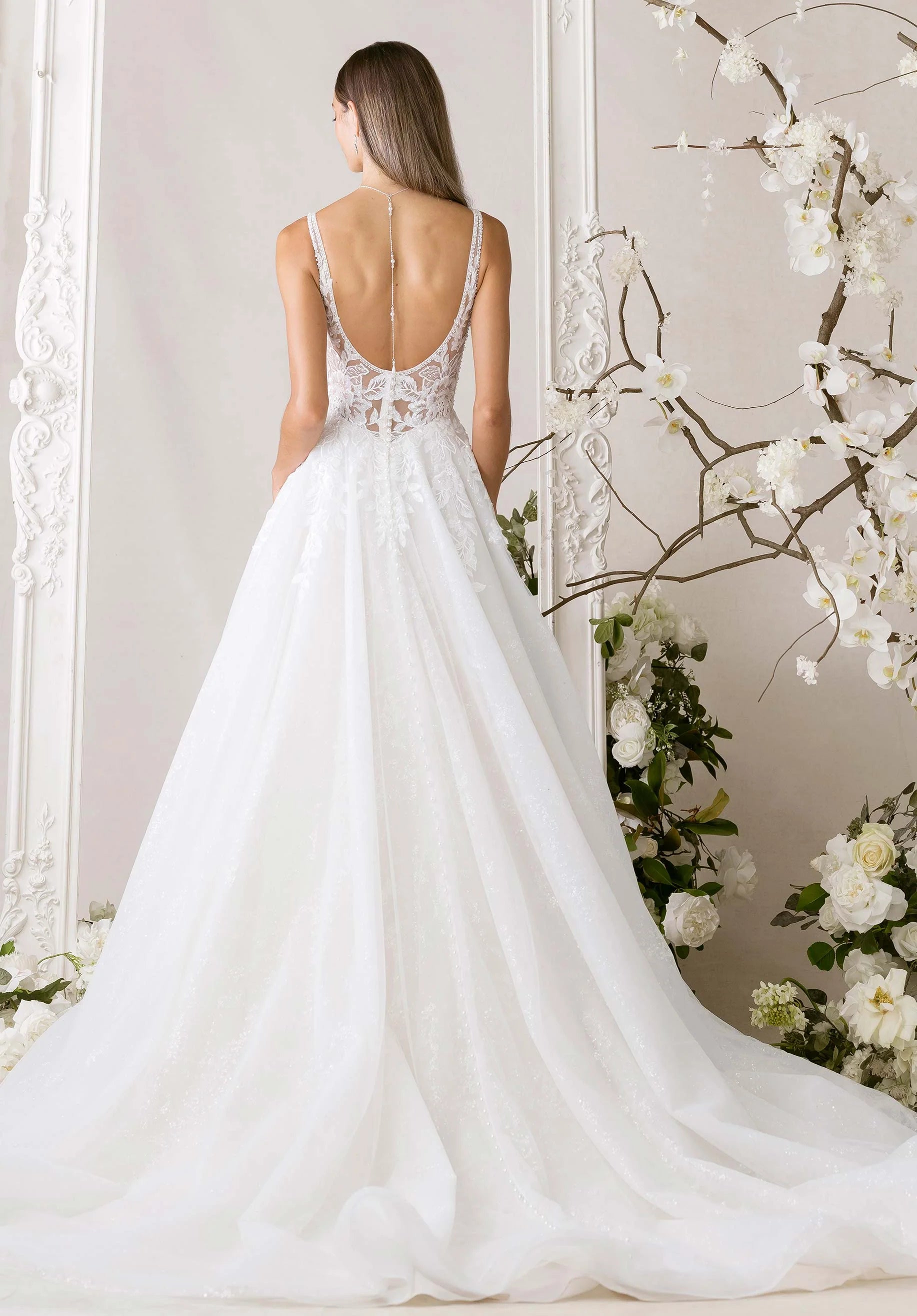 White wedding dress with floral details in a decorated room.