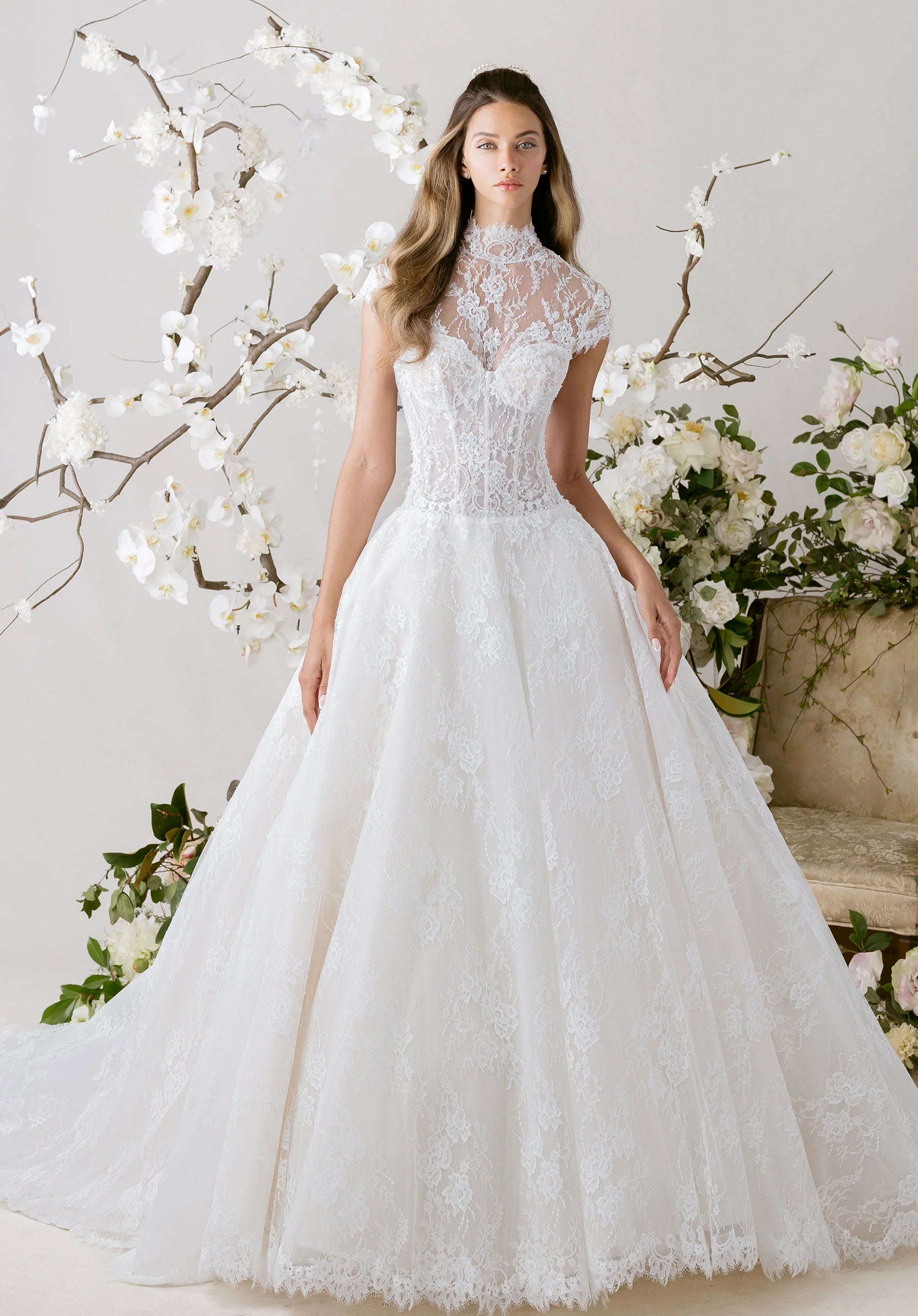 Woman wearing a white lace wedding dress with floral decorations in the background