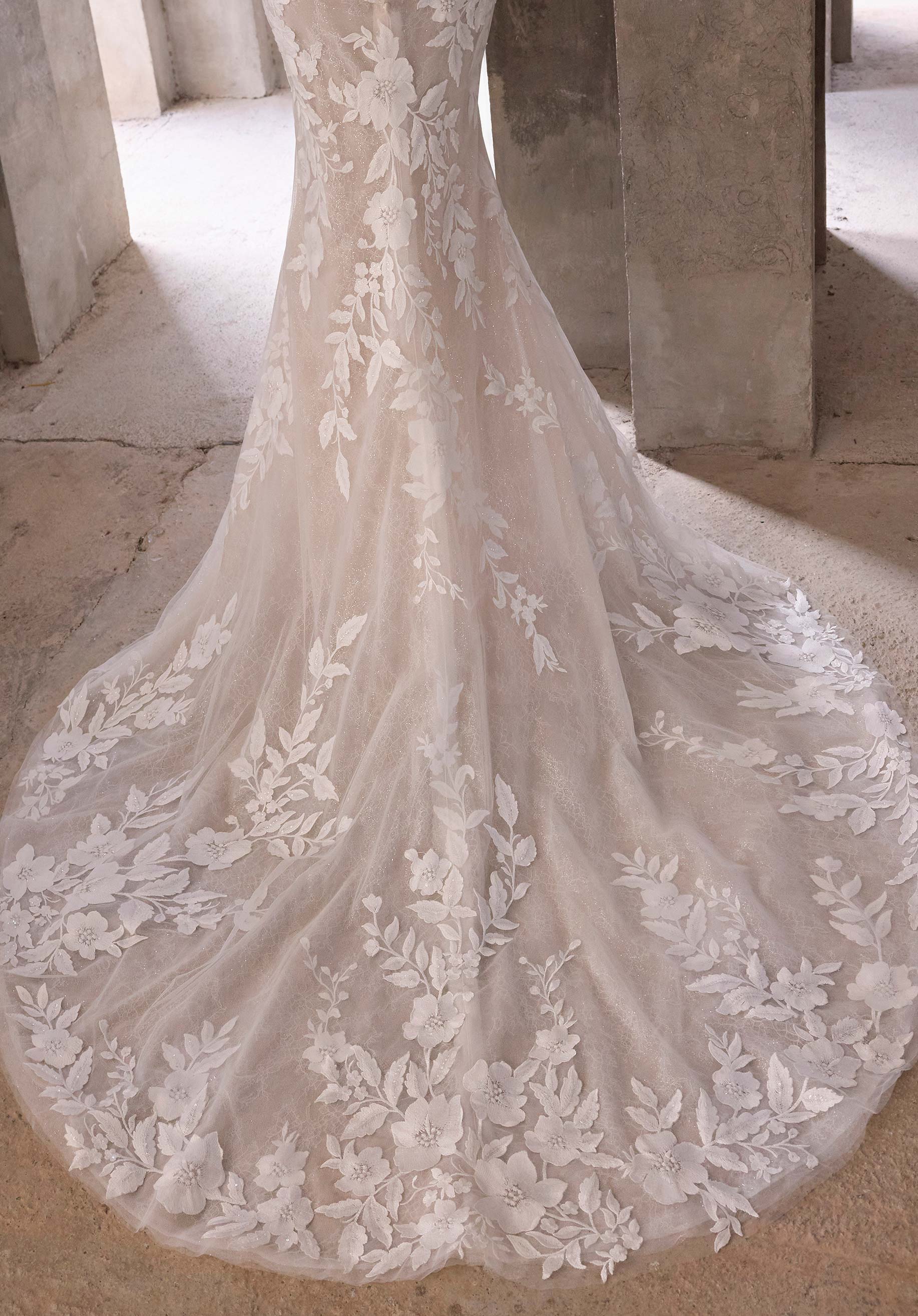 Elegant lace wedding dress with floral patterns on a stone floor.