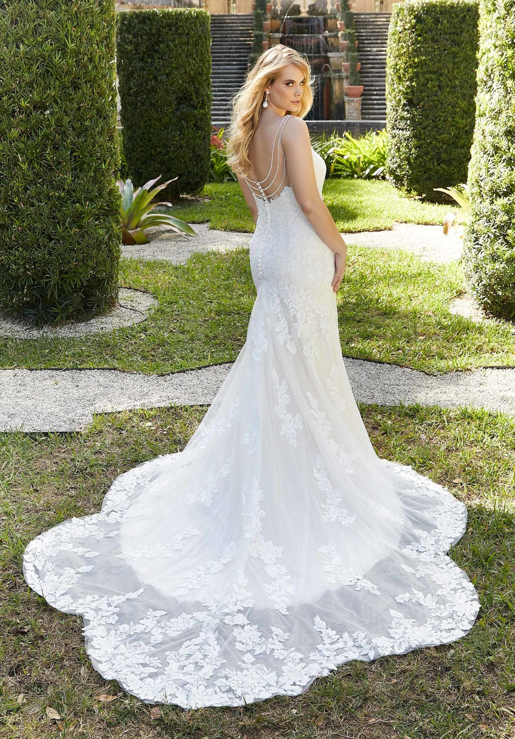 Woman in a white lace wedding dress standing in a garden.