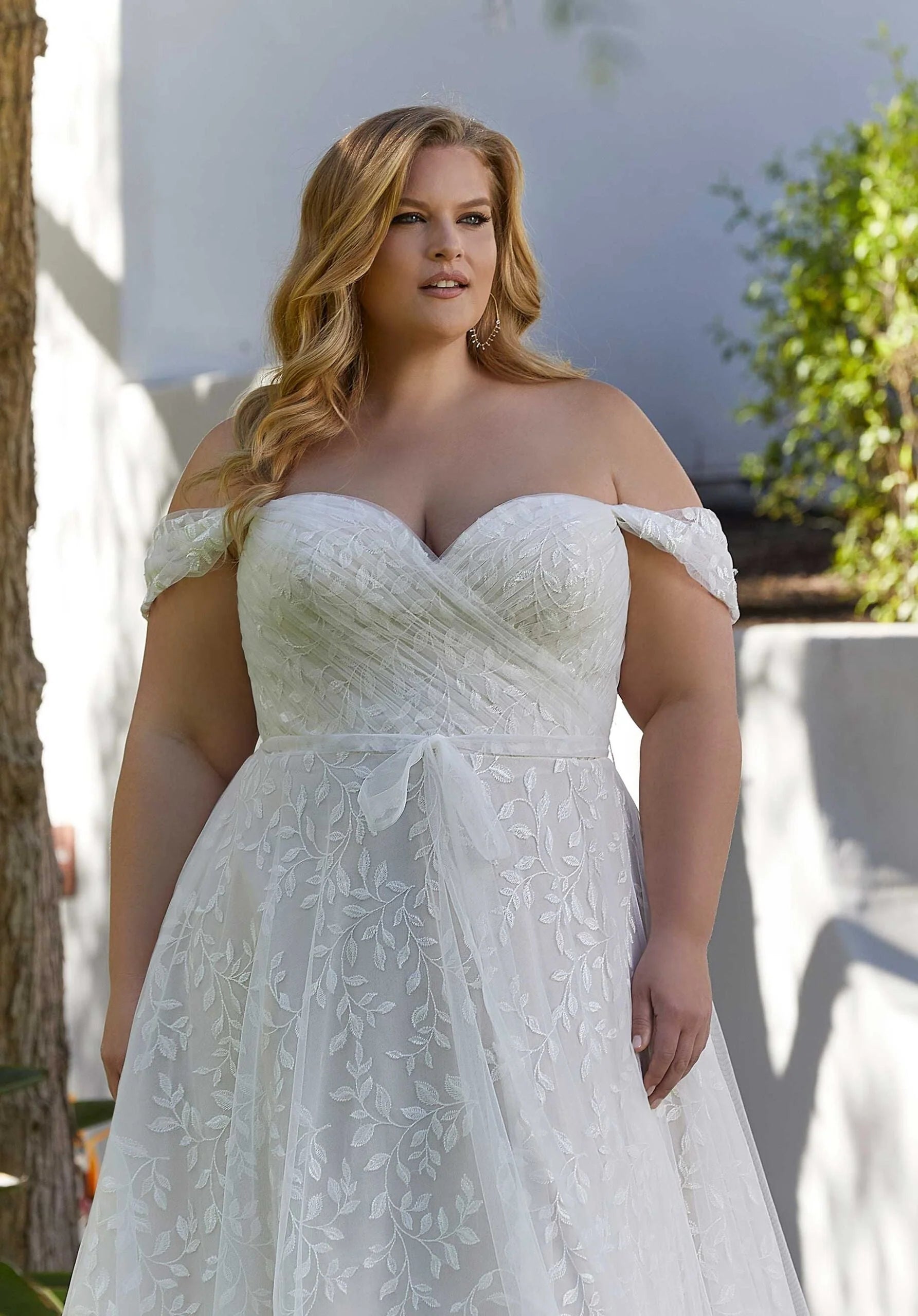 Woman wearing a white lace wedding dress outdoors.
