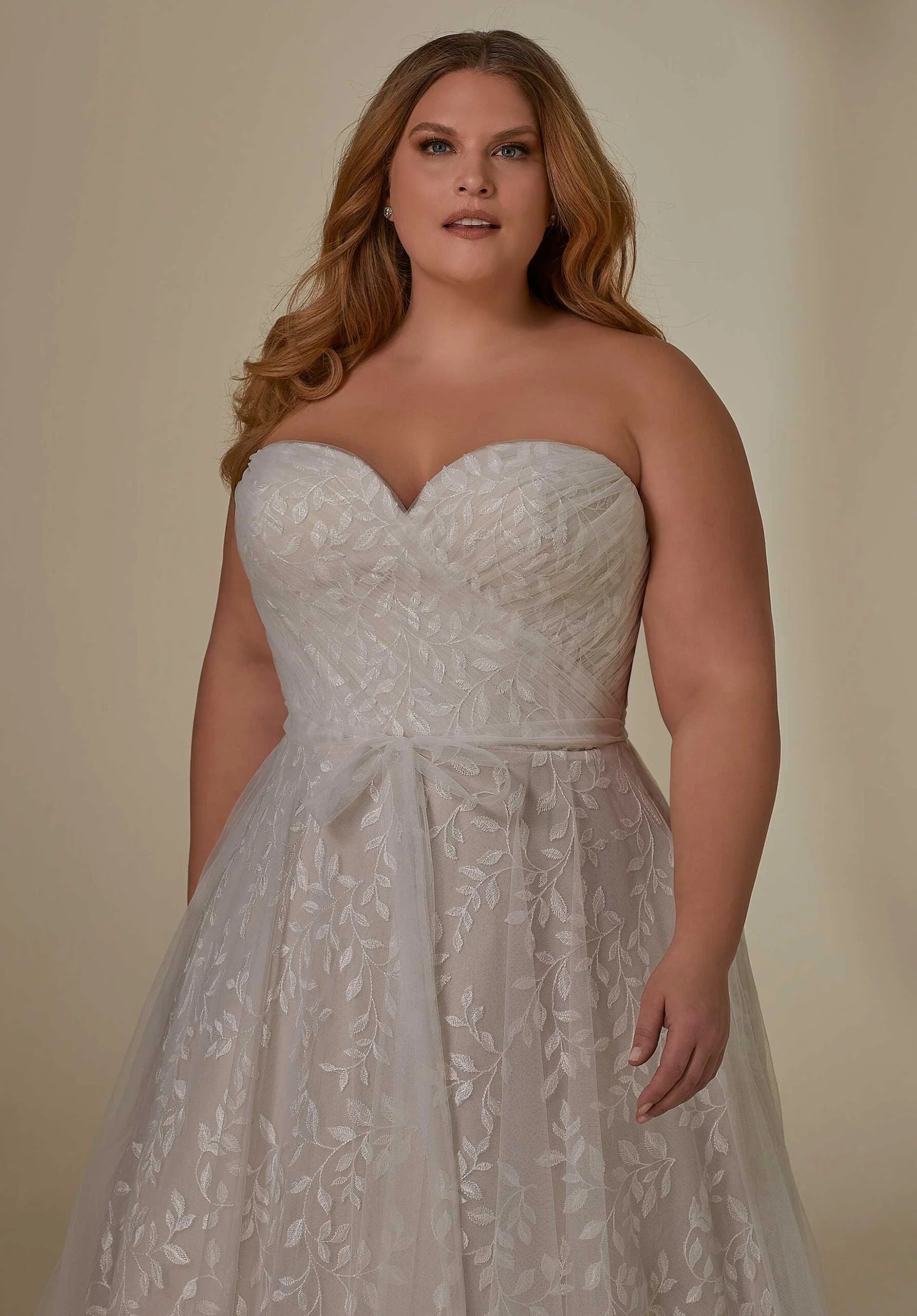 Woman wearing a strapless lace wedding dress against a plain background