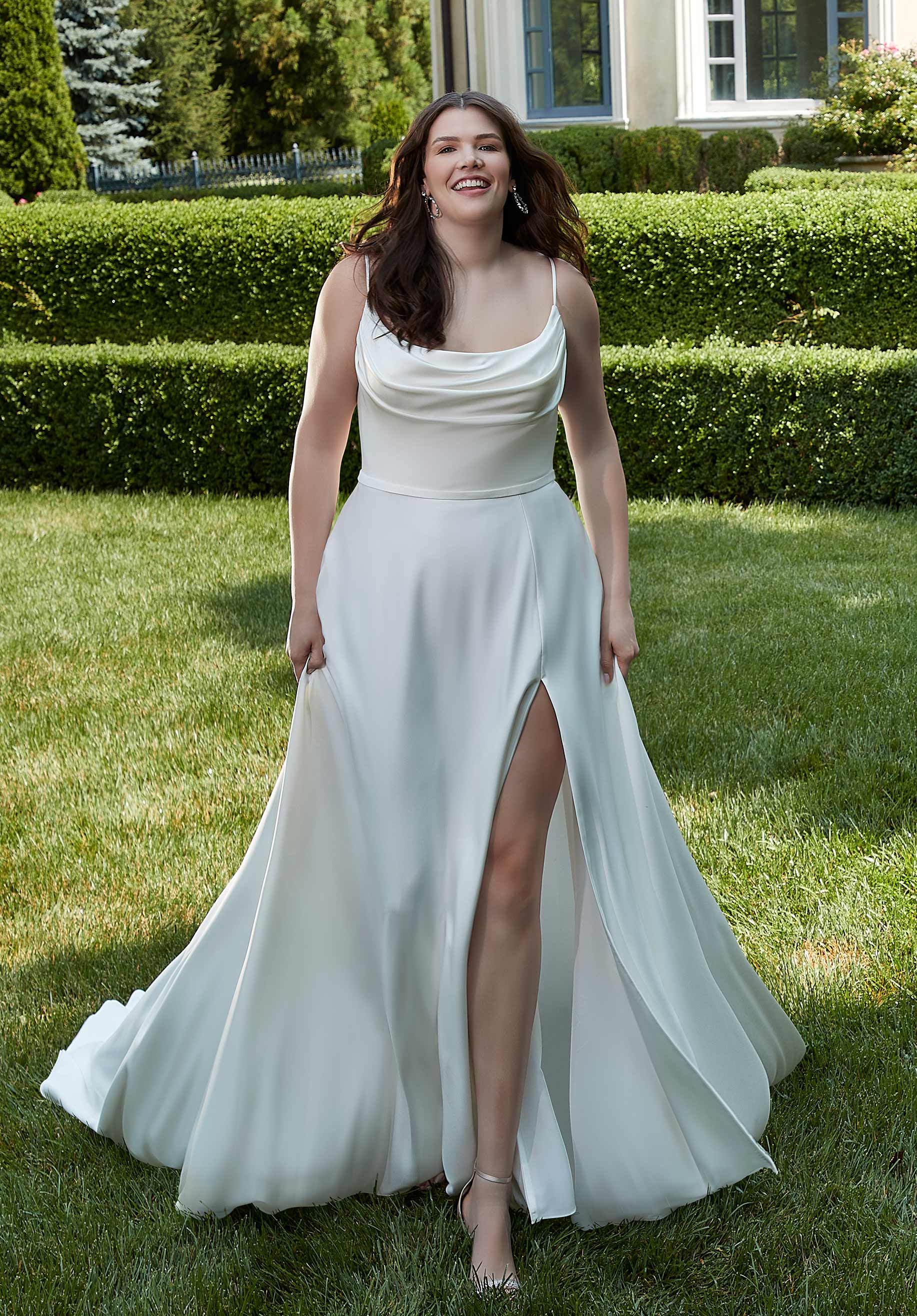 Woman in a white dress standing on grass with a garden background