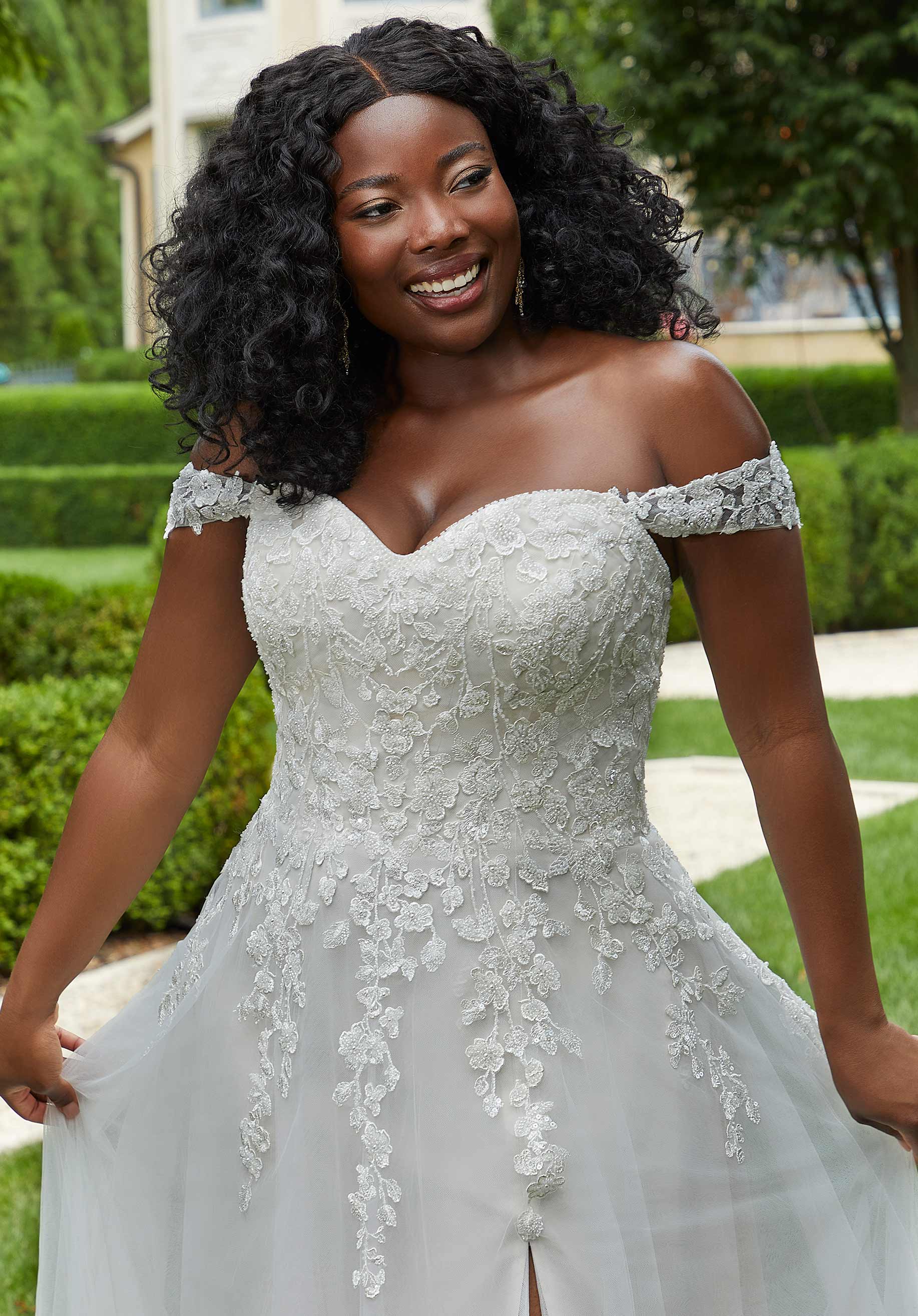 Woman wearing a white lace off-shoulder dress outdoors.
