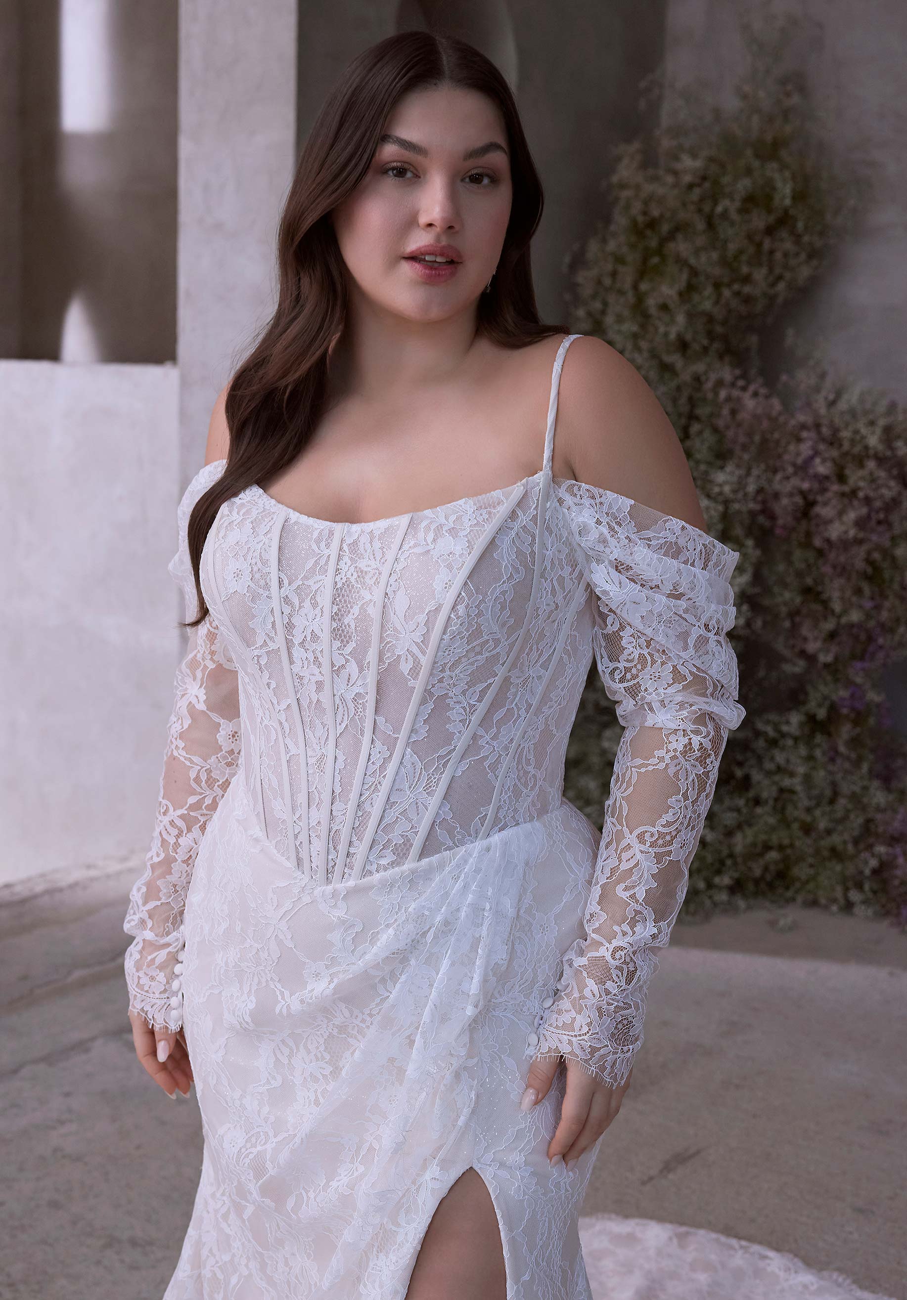 Woman wearing Constantia by Morilee Julietta - a white lace dress with long sleeves in an outdoor setting.