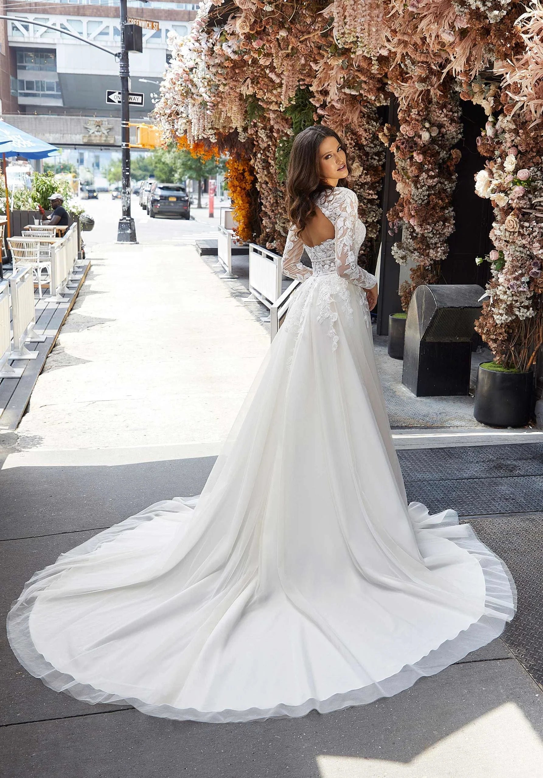 Woman in Judith by Morilee - a white wedding dress standing on a city street with floral decorations.