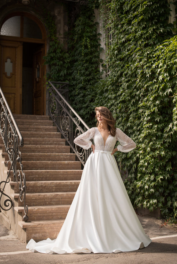 Woman in a white wedding dress standing on stone steps with greenery in the background