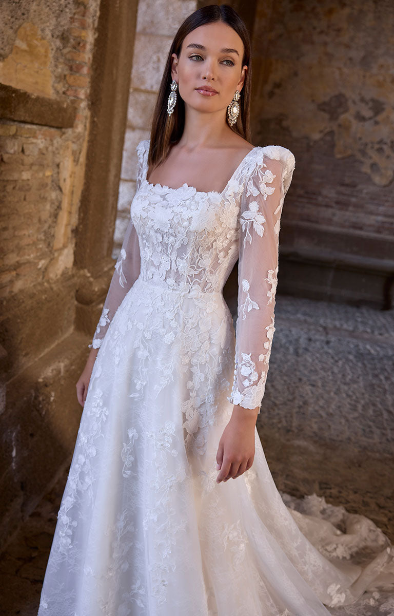 Woman wearing 63273 Apollonia by Veni Infantino - Floral Lace A-Line Wedding Dress with Square Neckline and Puff Sleeves in an outdoor setting.