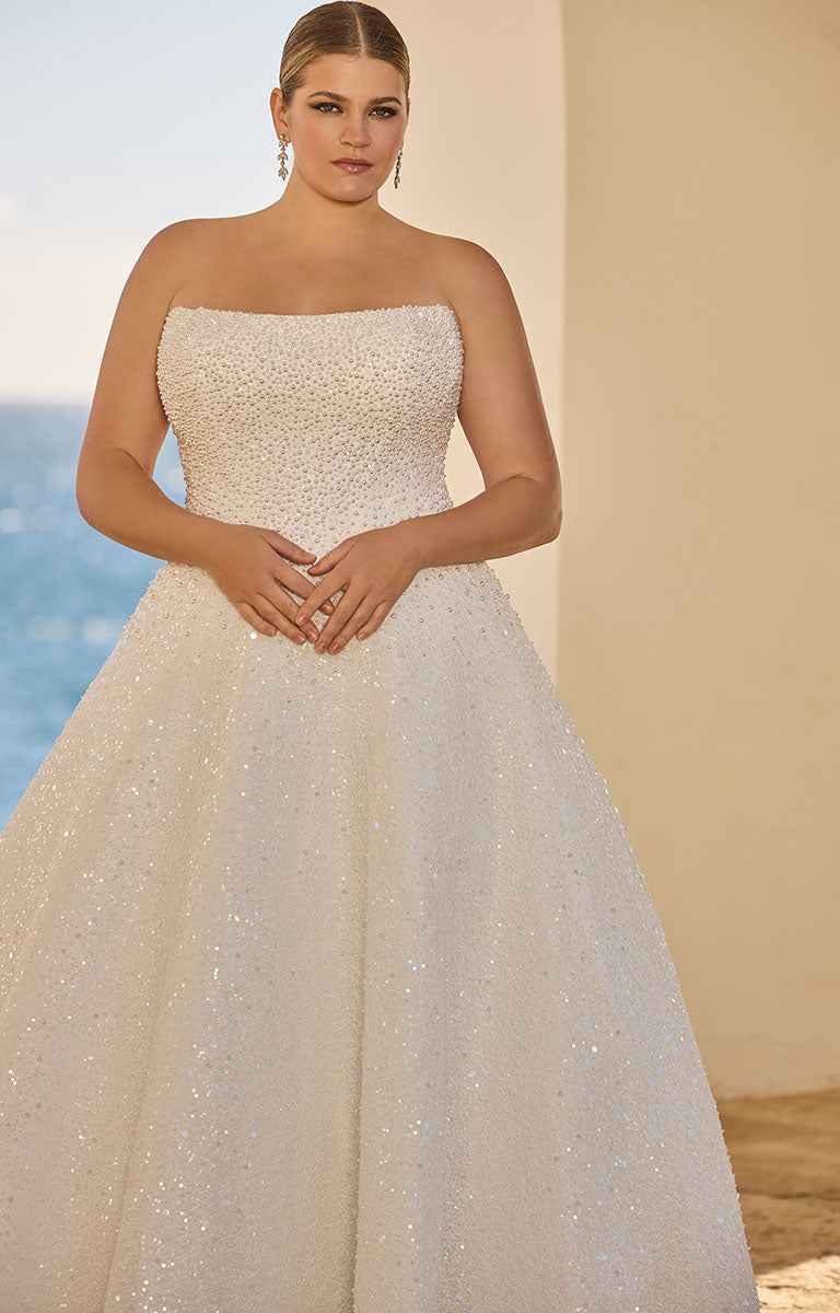 Woman wearing 63120 Hilani by Veni Infantino - Beaded Pearl Embellished Wedding Dress with Delicate Button Detail on a beach.